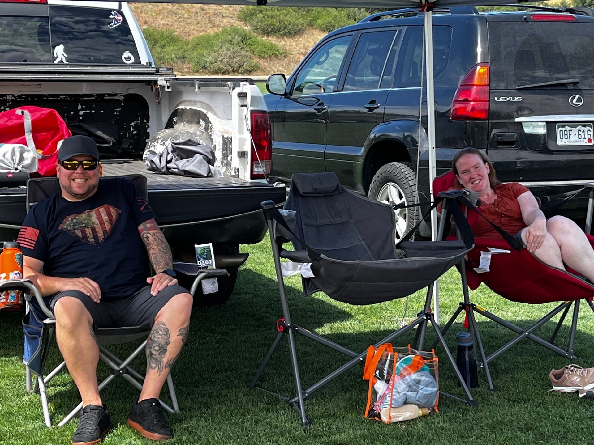 A man and a woman are sitting in folding chairs in front of a truck.