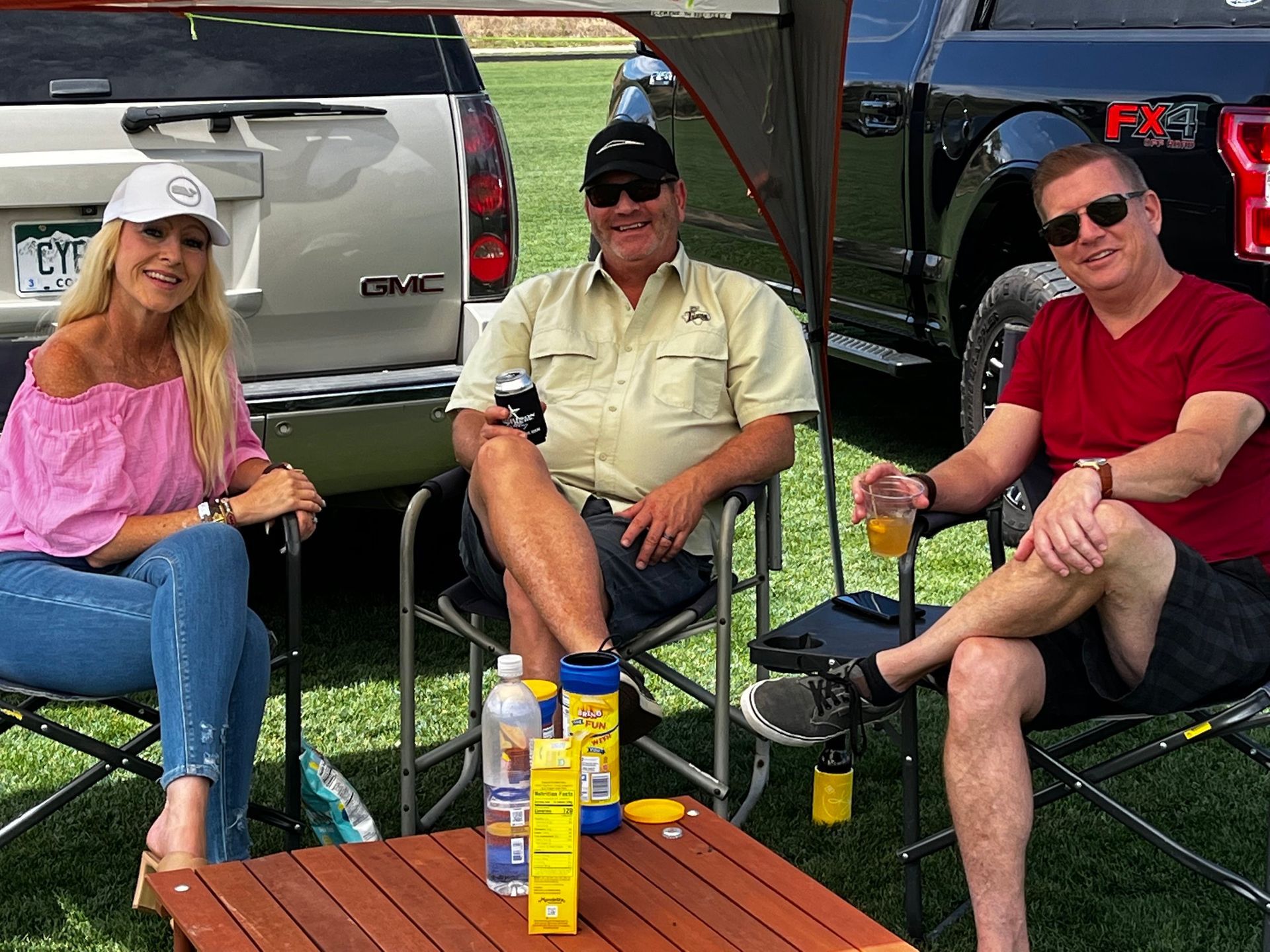 Three people are sitting in chairs in front of a truck.