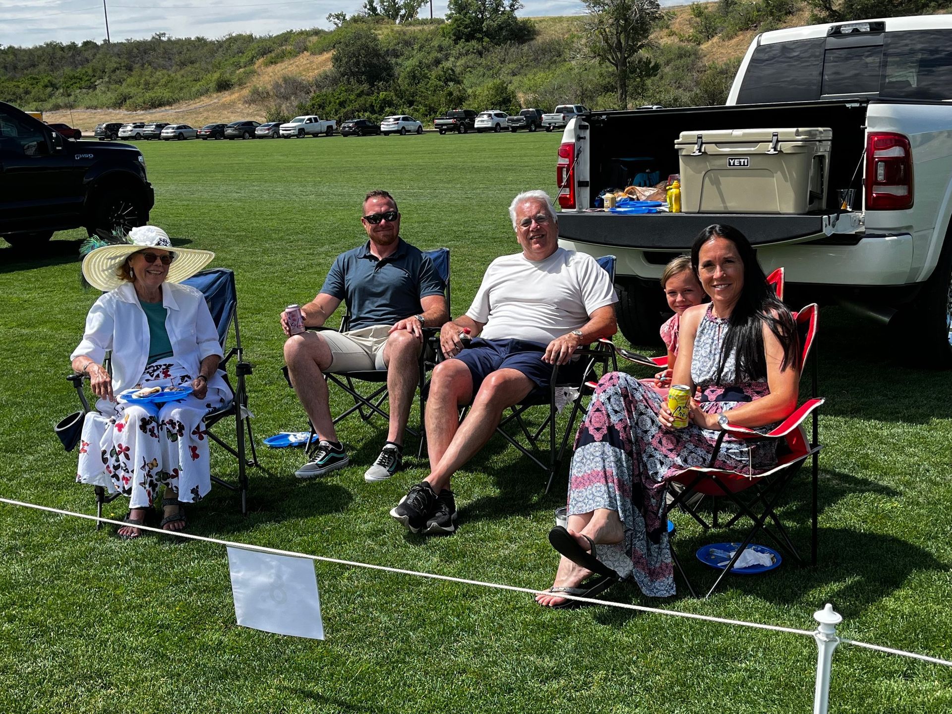 A group of people are sitting in chairs in a field next to a truck.