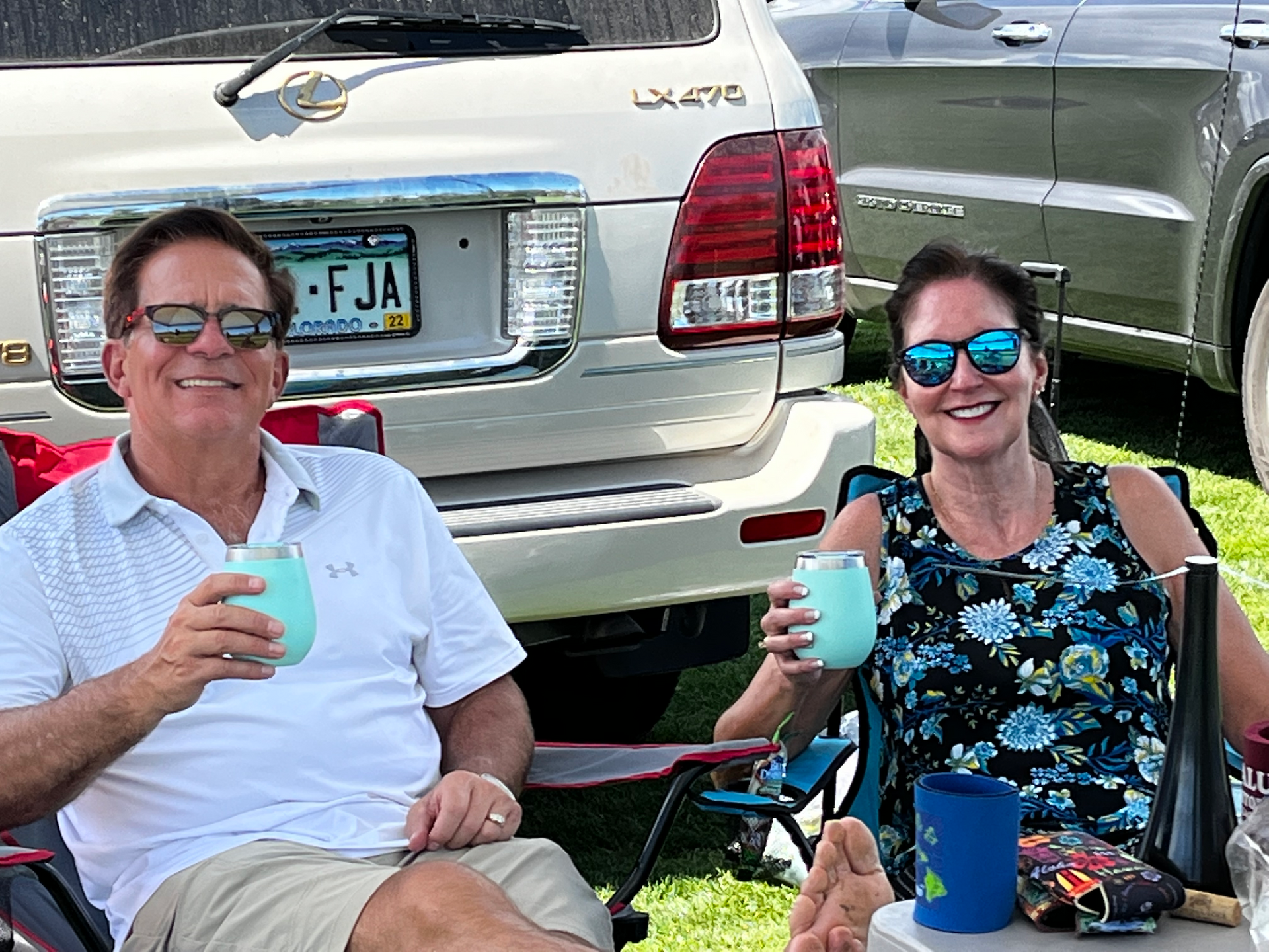 A man and a woman are sitting in front of a car with a license plate that says fja