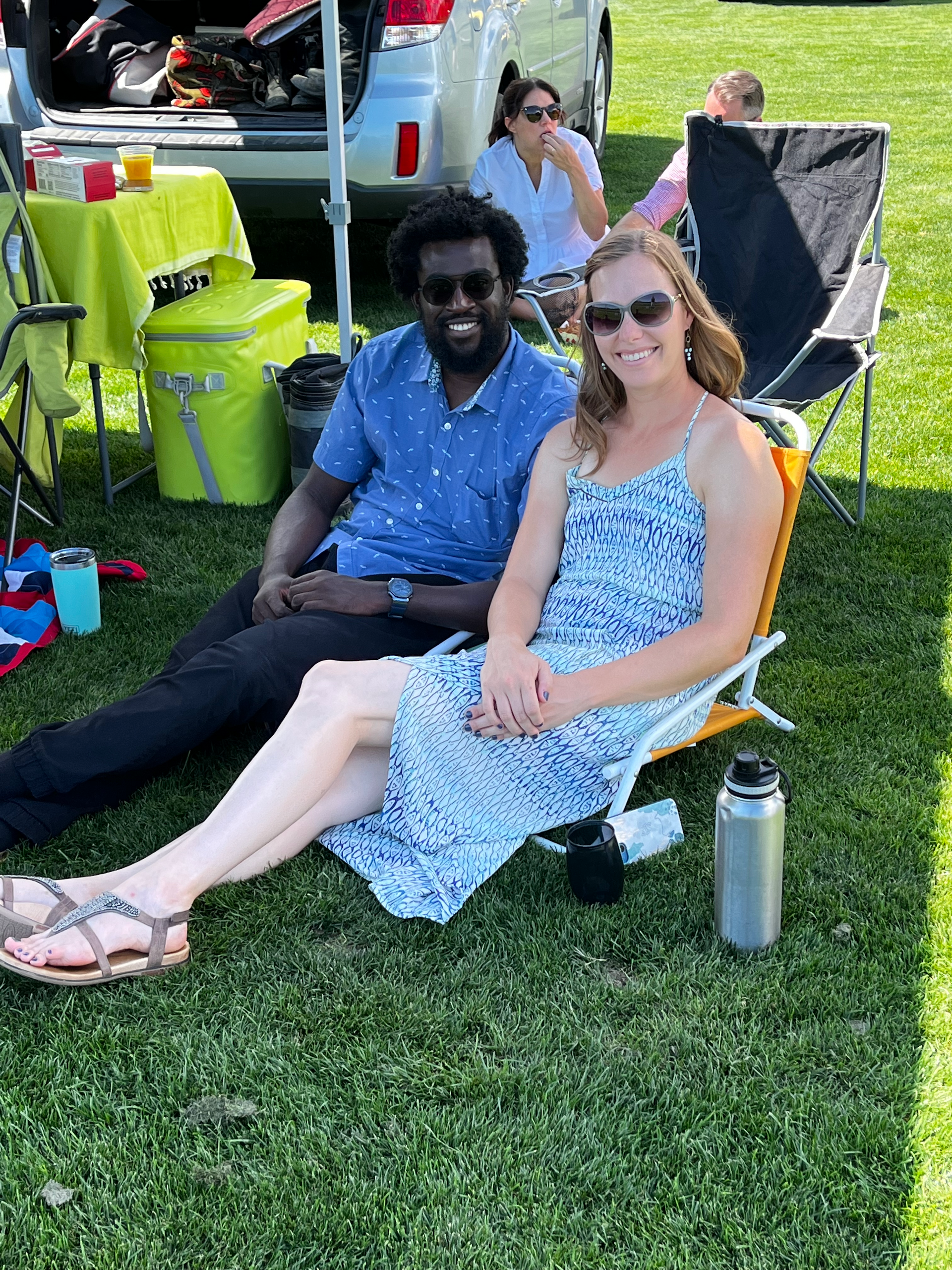 A man and a woman are sitting in chairs in the grass.
