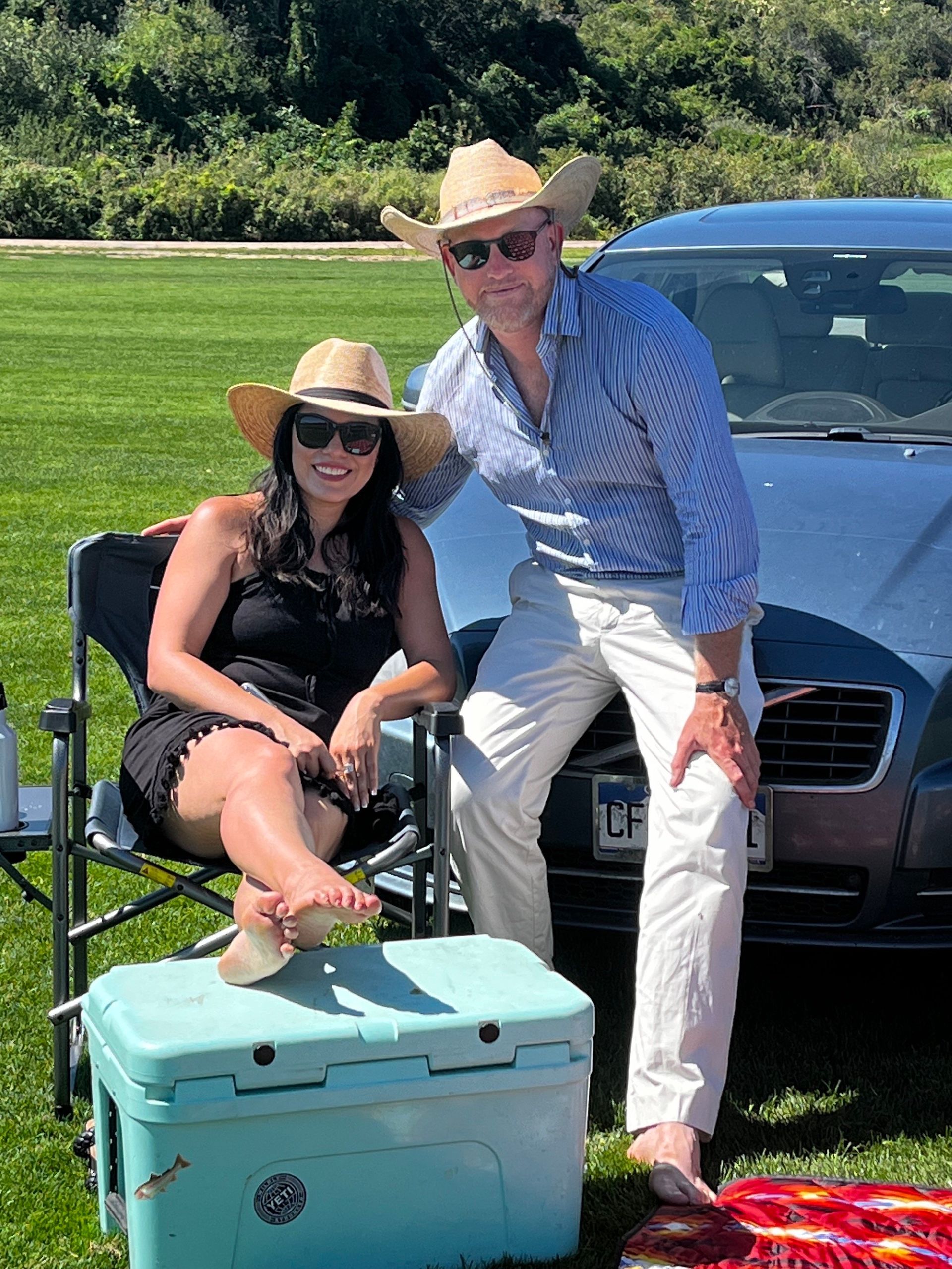 A man and a woman are posing for a picture in front of a car.