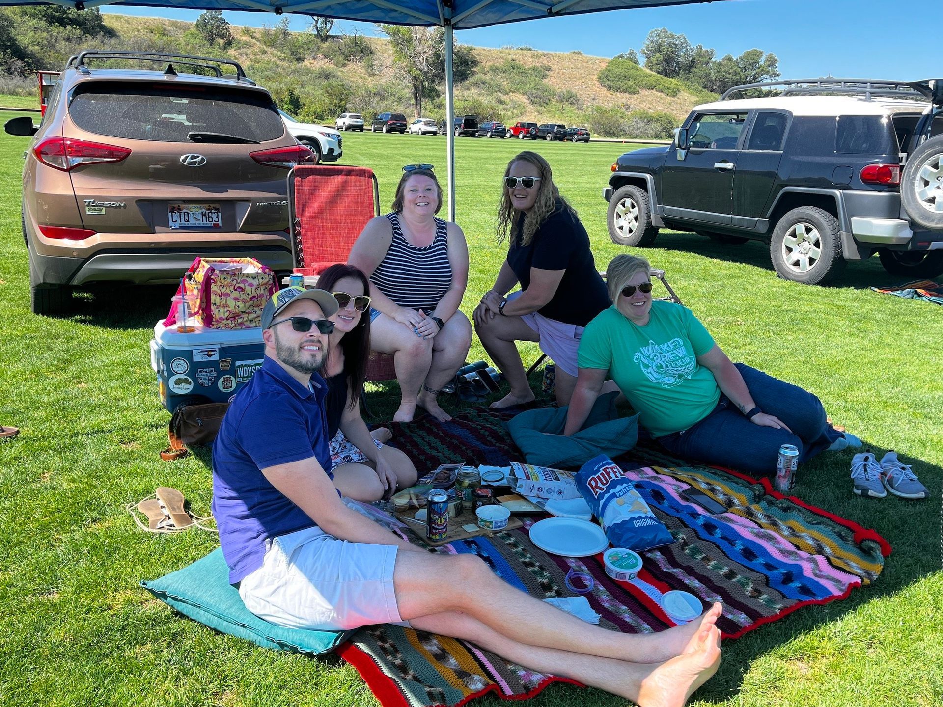 A group of people are sitting on a blanket in a field.