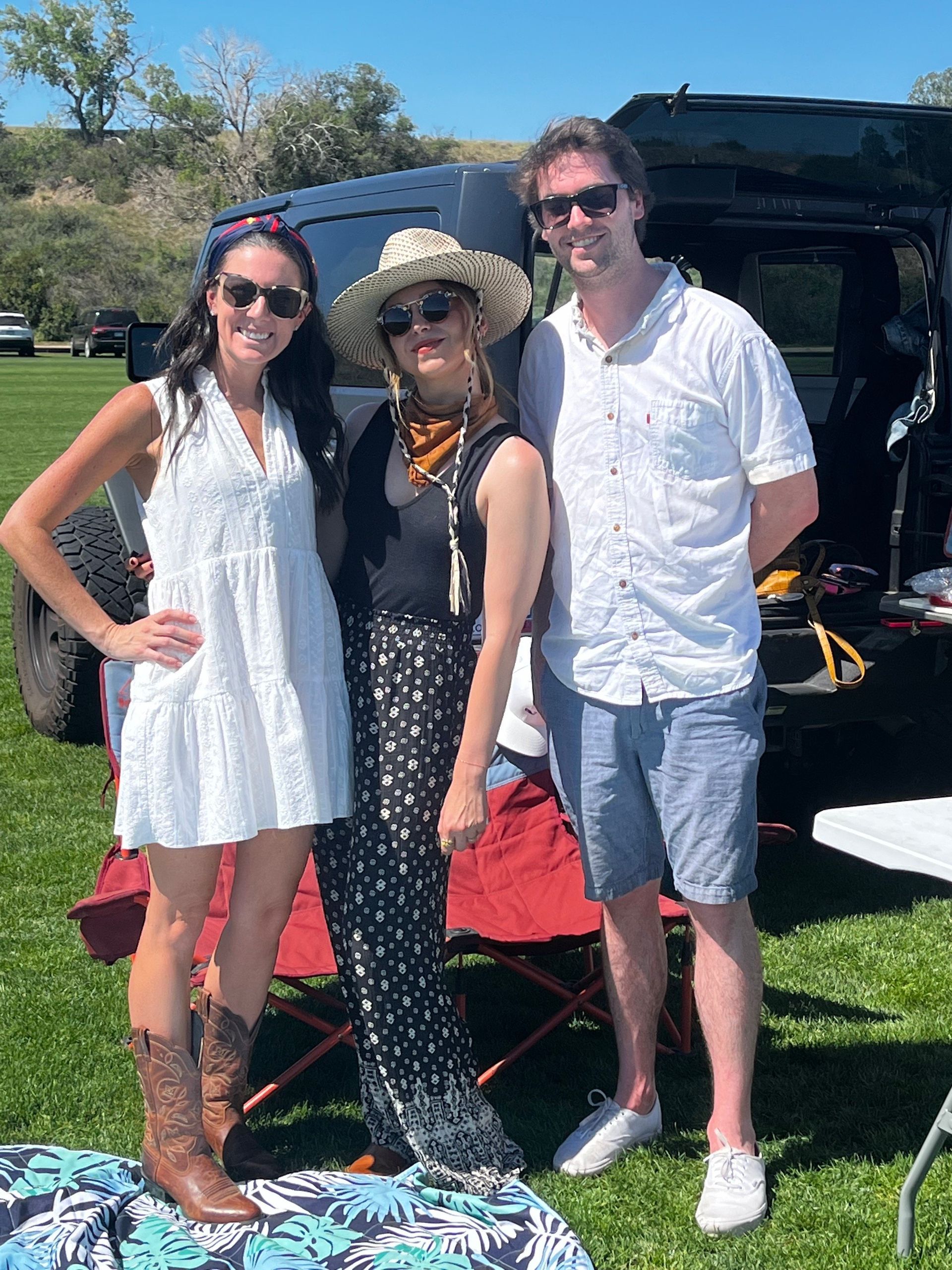 Three people are posing for a picture in front of a jeep.