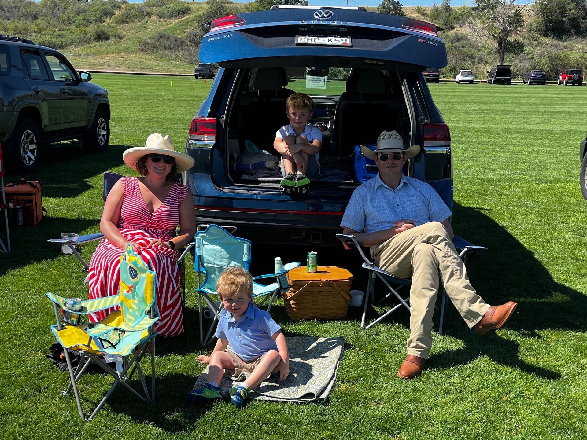 A family is sitting in the back of a car in a field.