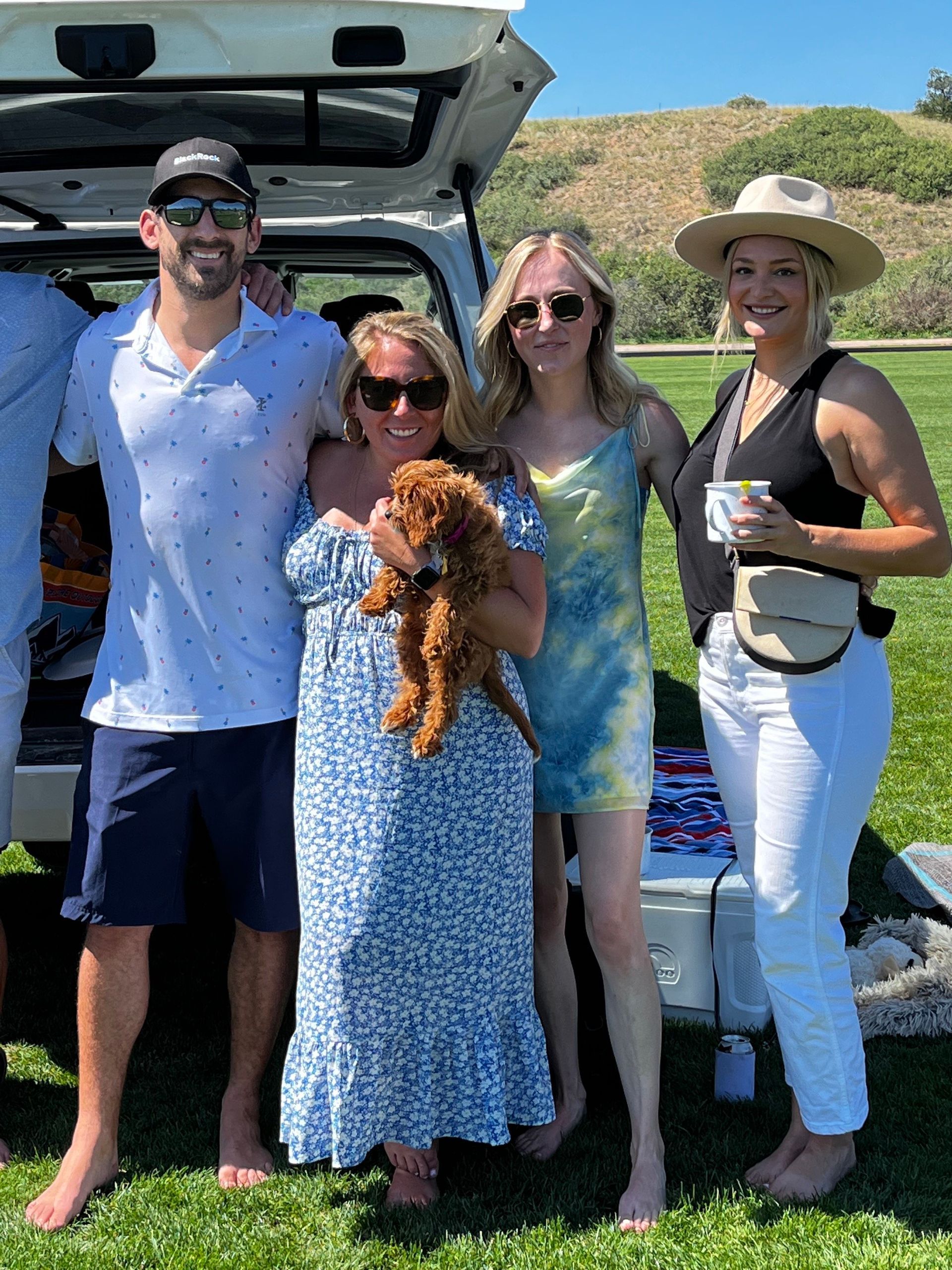 A group of people are posing for a picture in front of a car.
