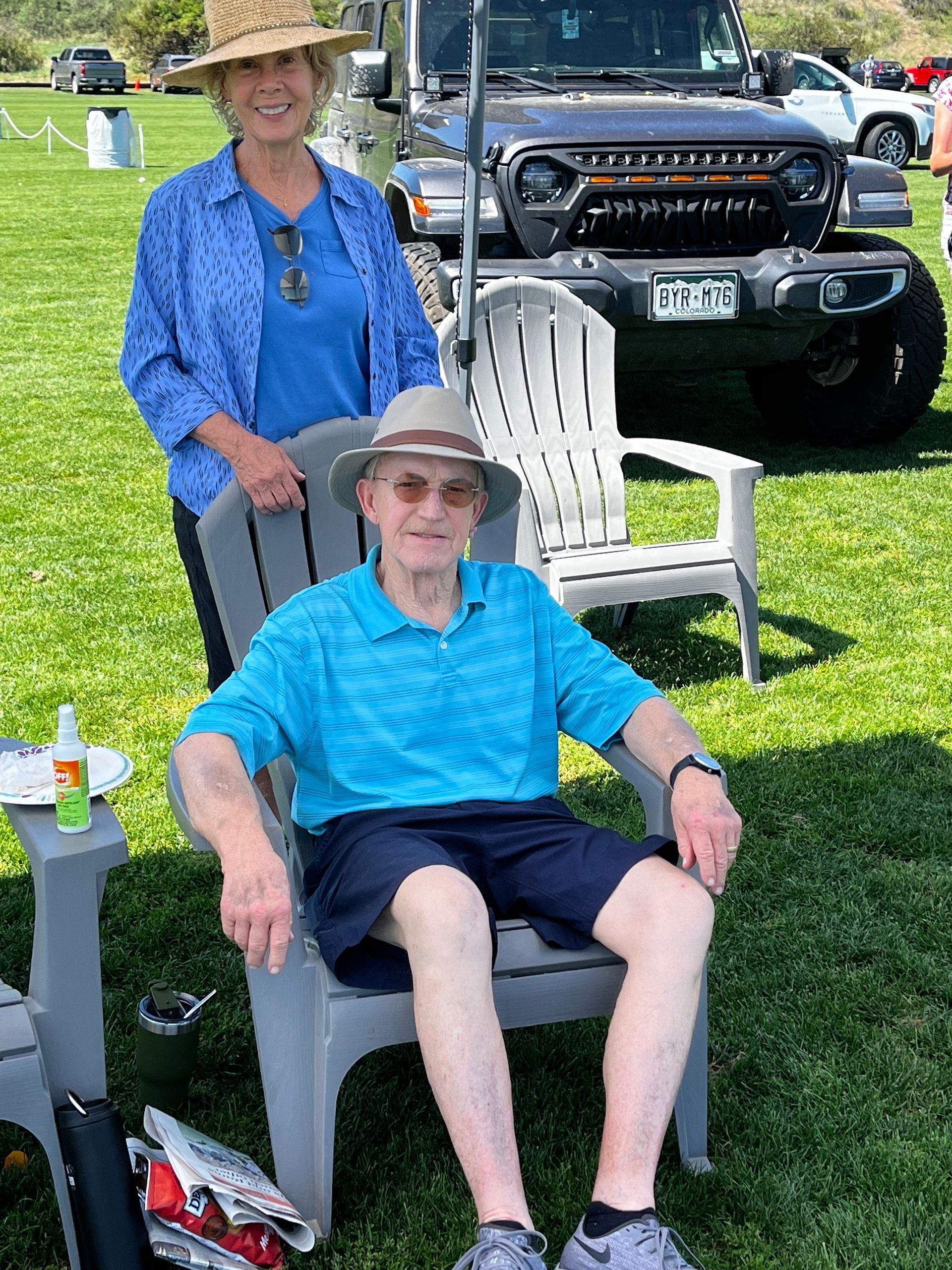 A man is sitting in a chair with a woman standing behind him.