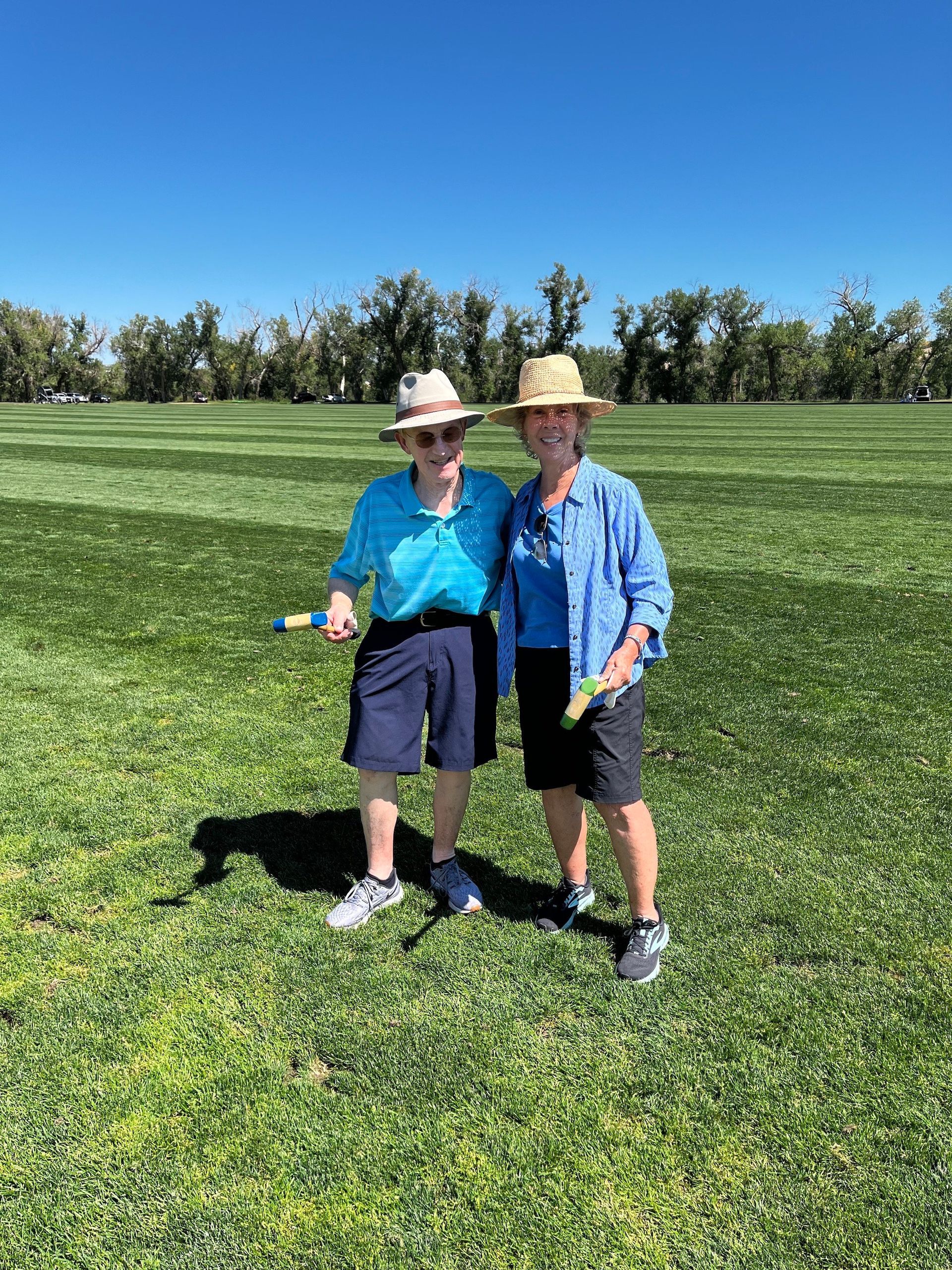Two women are standing next to each other in a grassy field.