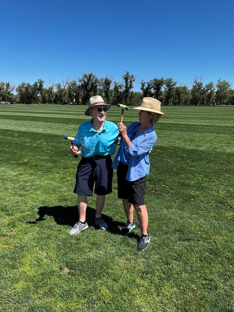 Two people are standing on a golf course holding golf clubs.