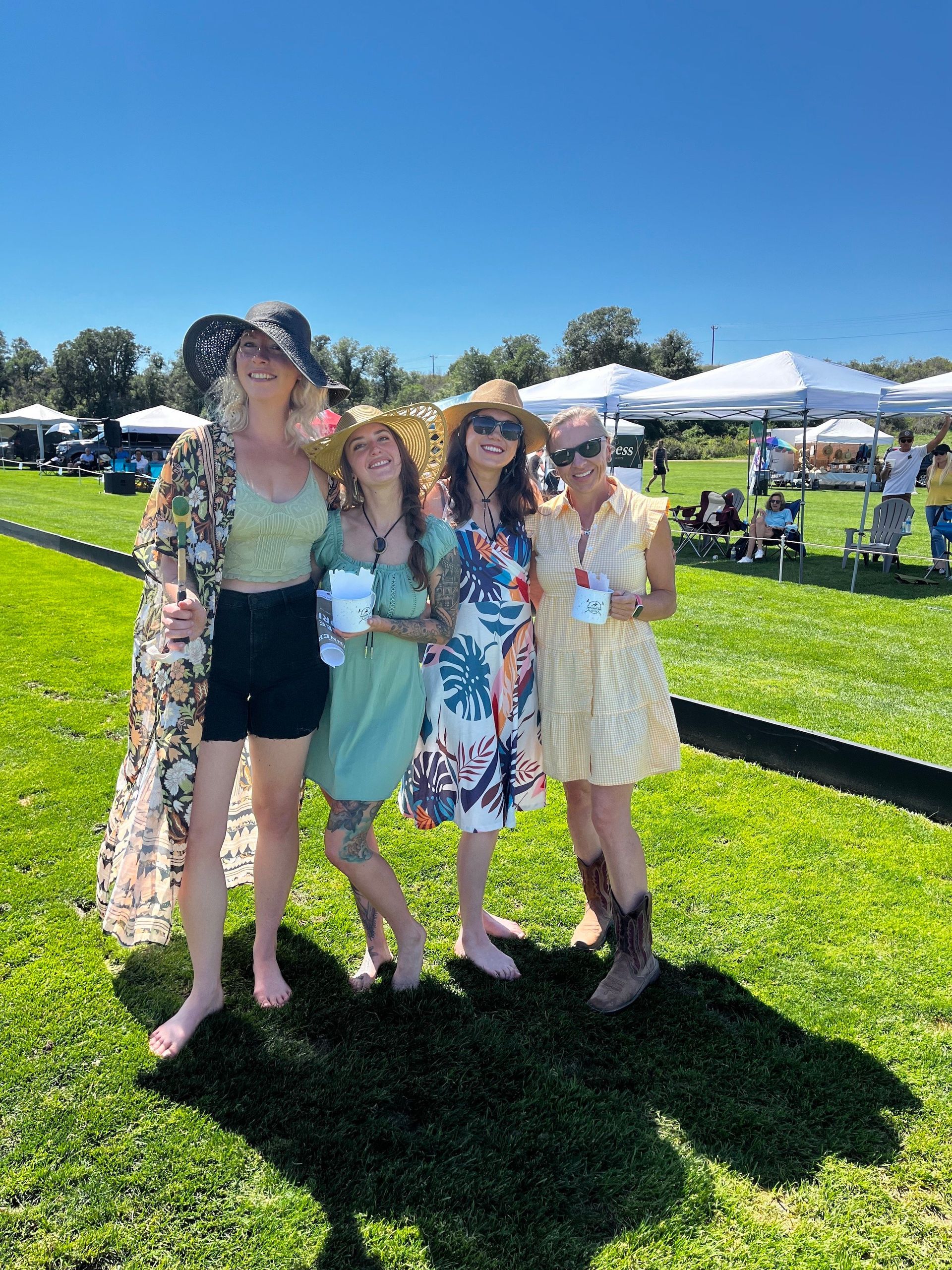 A group of women are posing for a picture in a grassy field.