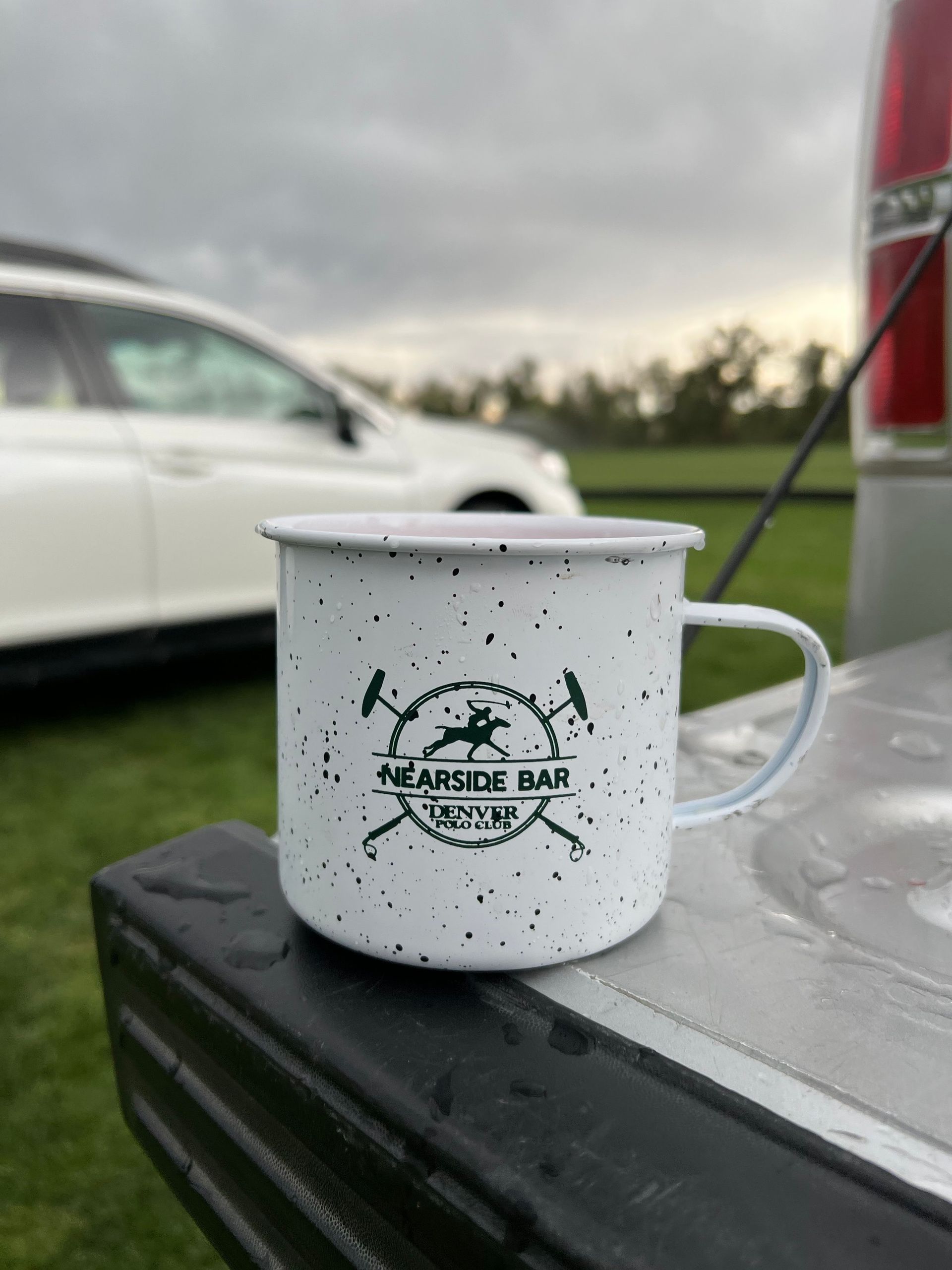 A white mug is sitting on the back of a truck.
