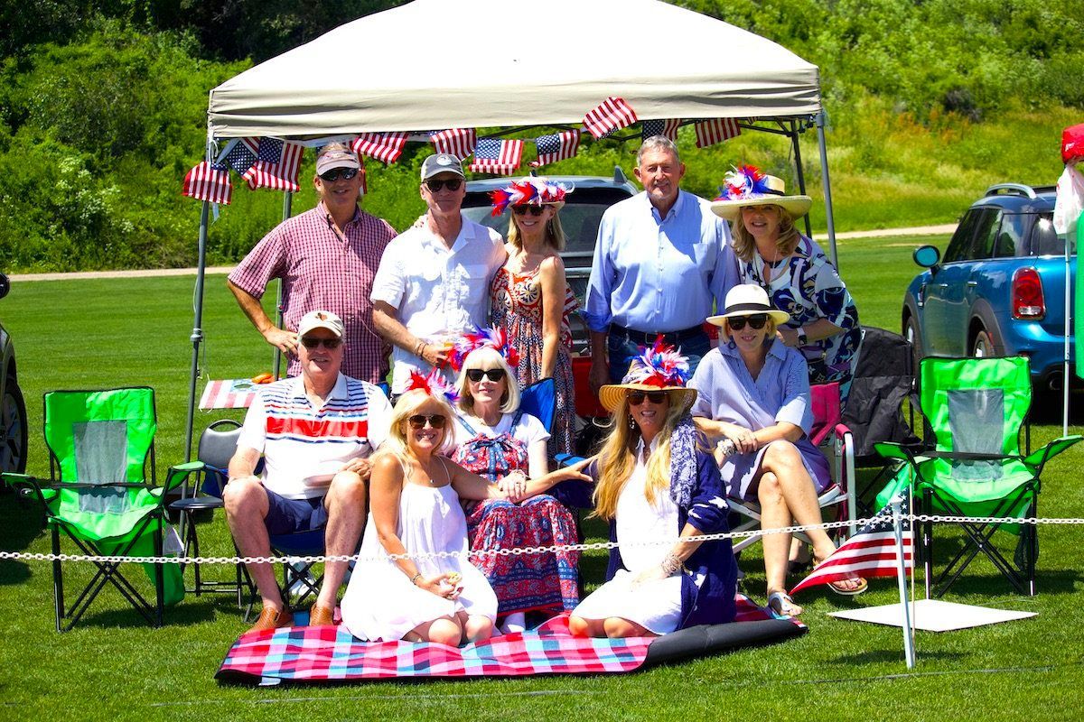 A group of people are sitting under a tent in a field.