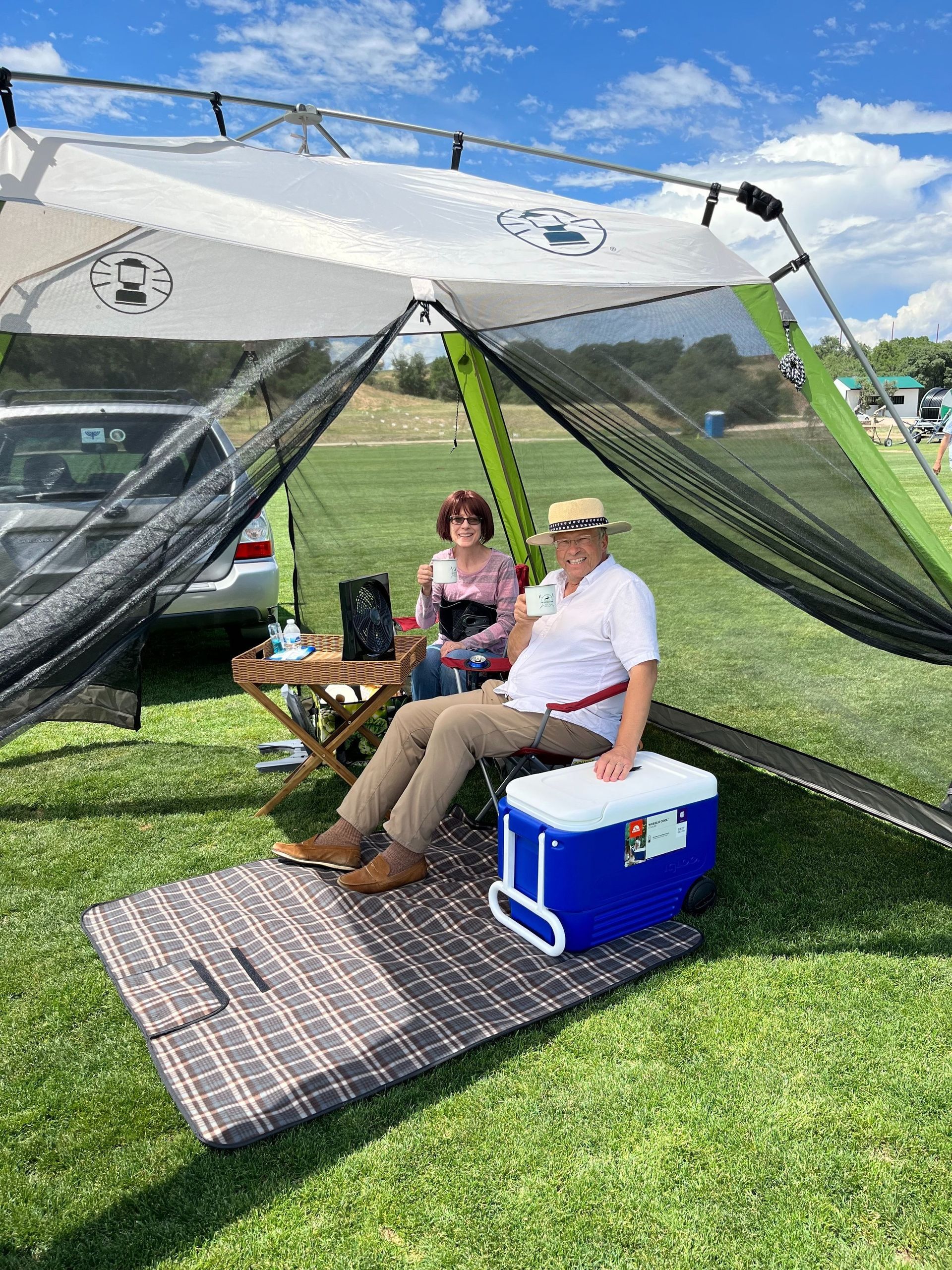 A man and a woman are sitting under a tent in a field.