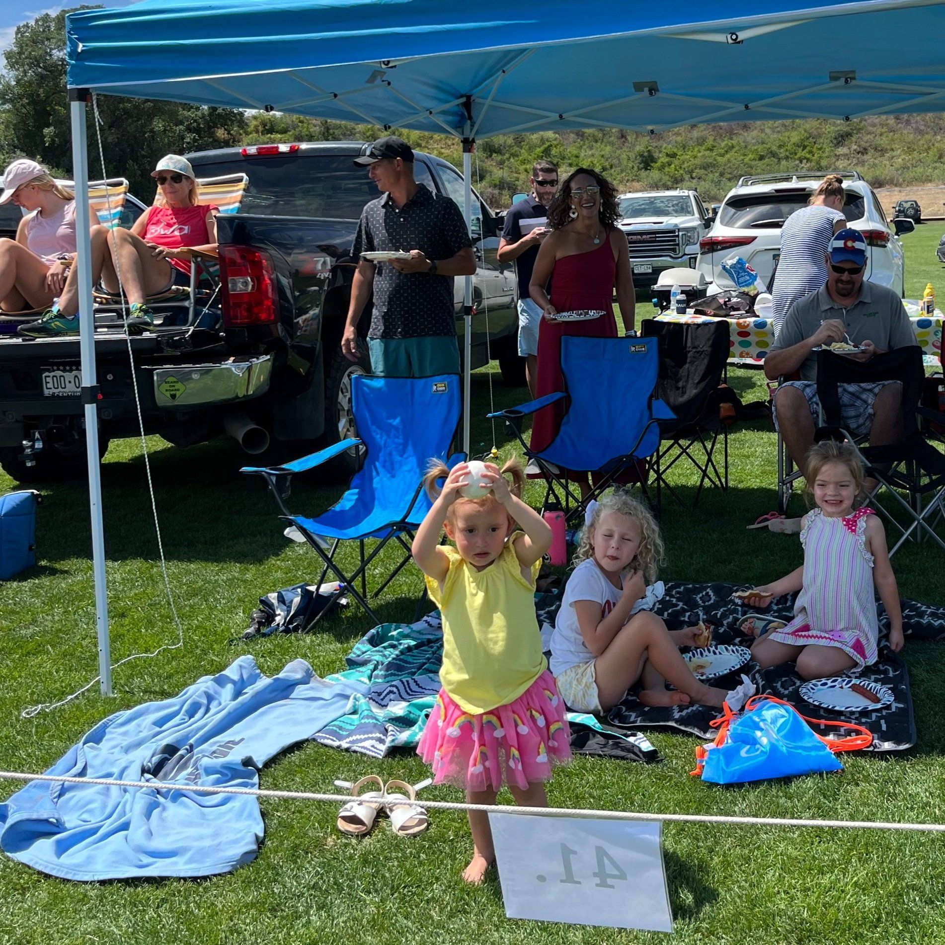 A group of people are sitting under a tent in a field.