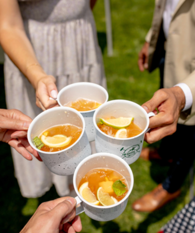 A group of people are holding up cups of tea with lemon slices