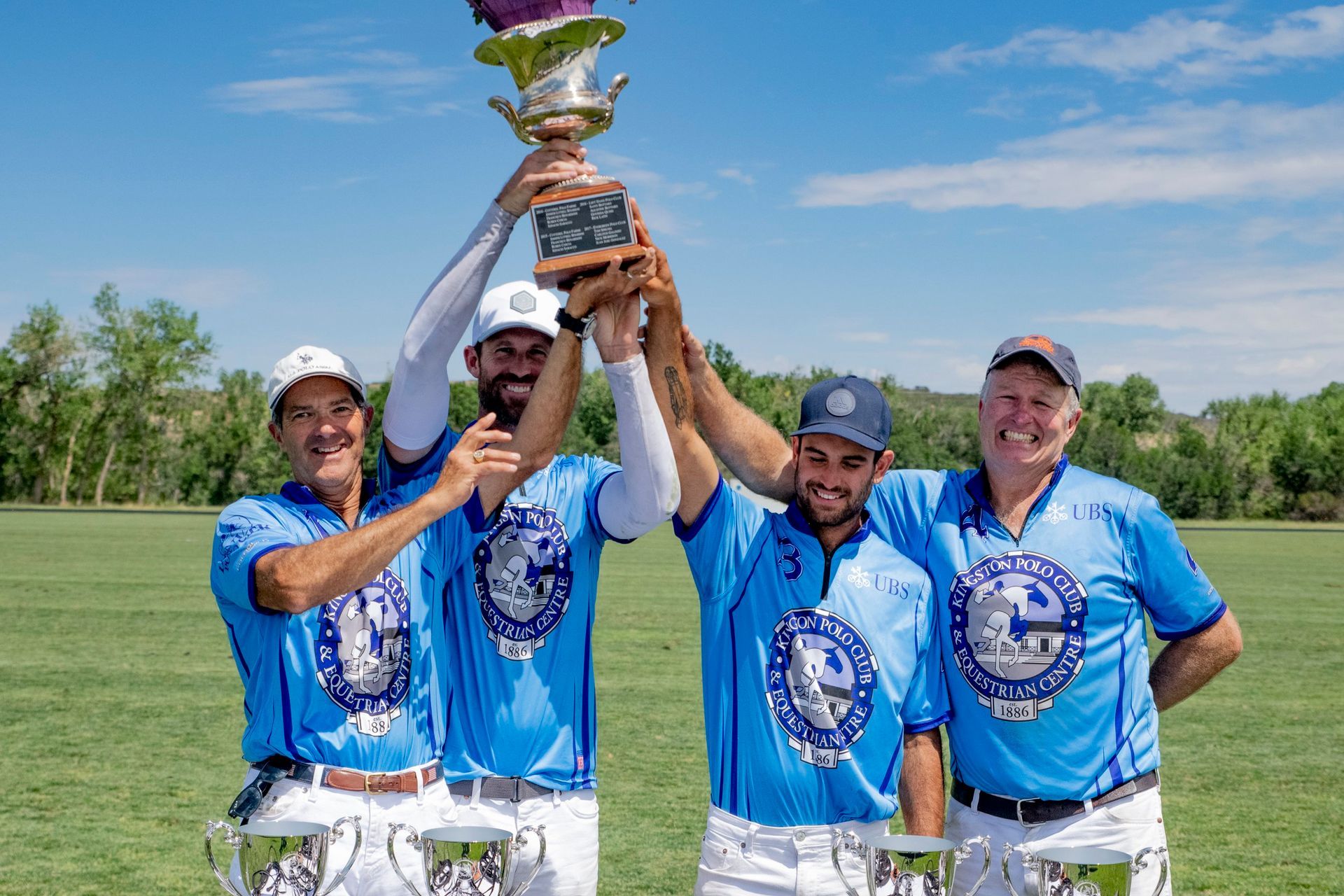 A group of men are holding up a trophy in a field.