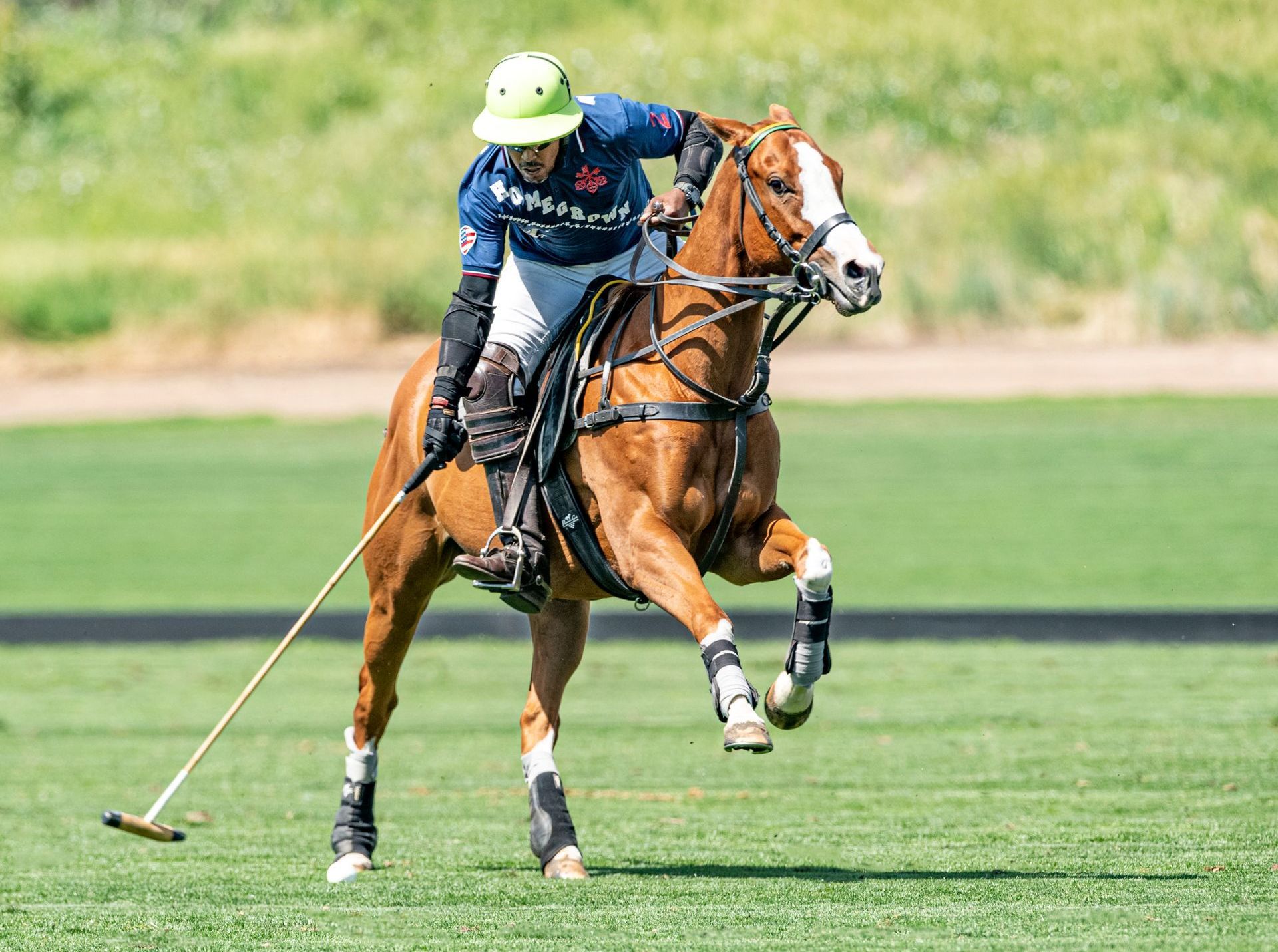 A man is riding a horse while playing polo on a field.