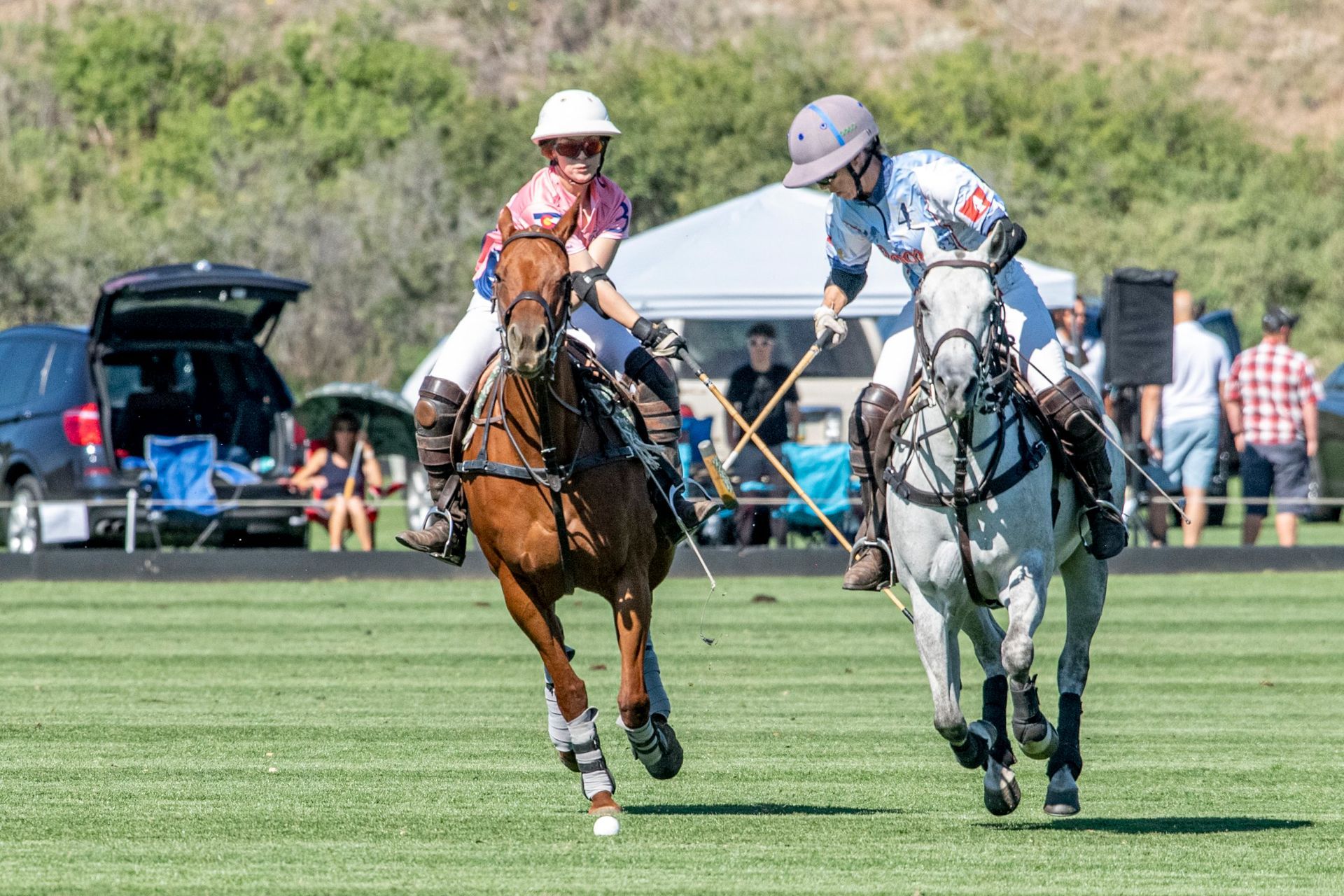 Two people are riding horses on a polo field.