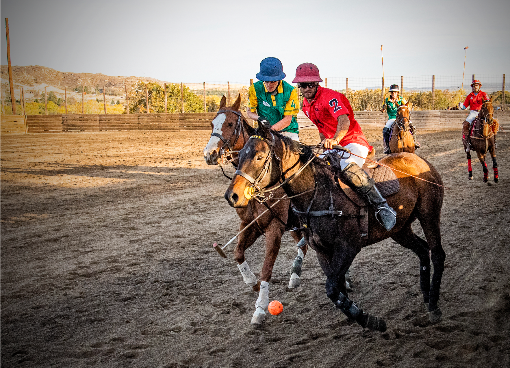A group of people are playing polo on horses in a dirt field.