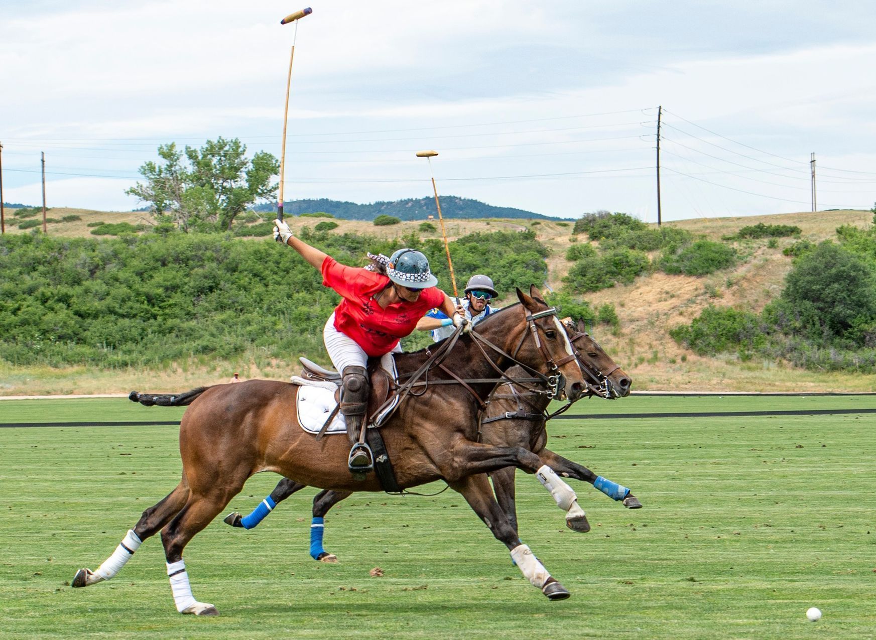 A man is riding a horse while playing polo on a field.