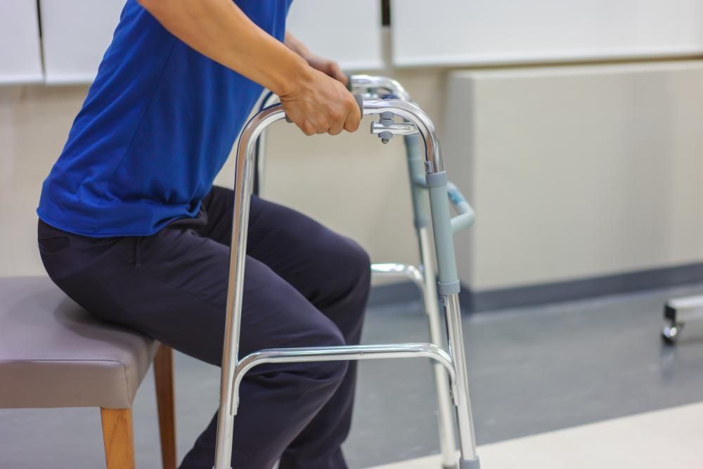 A Person Is Sitting on A Chair Using a Walker — St Vincents Physiotherapy & Day Rehab in East Lismore, NSW