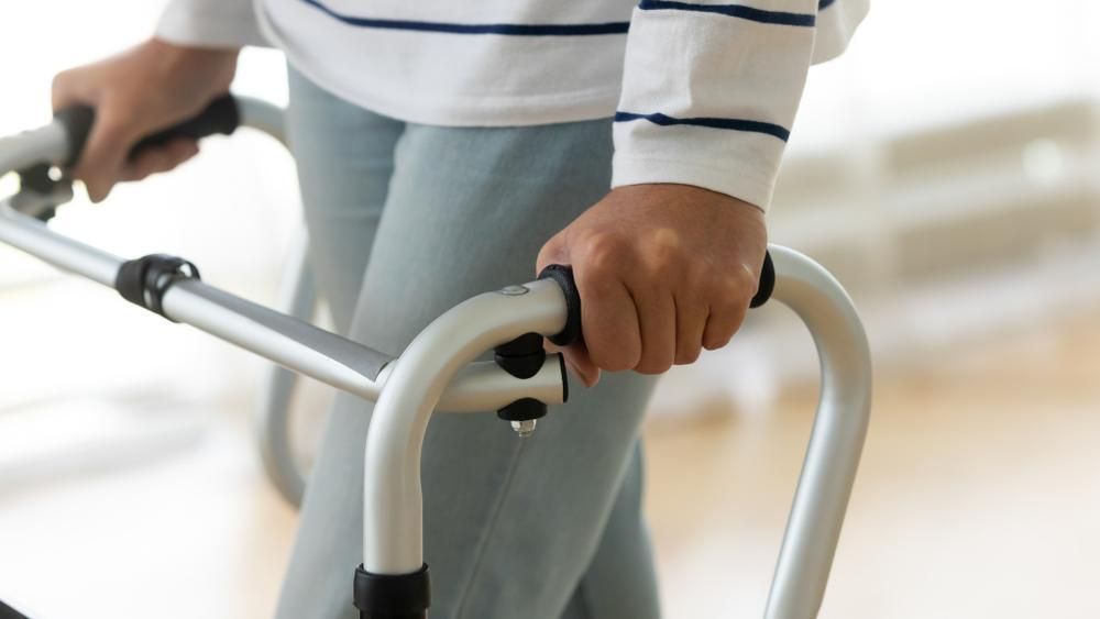 A Person Is Using a Walker to Help Them Walk — St Vincents Physiotherapy & Day Rehab in East Lismore, NSW