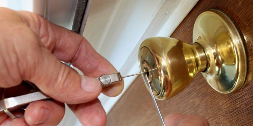 A person is fixing a door knob with a screwdriver.