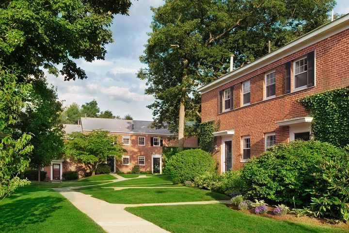 A row of brick apartments with a sidewalk in front of them
