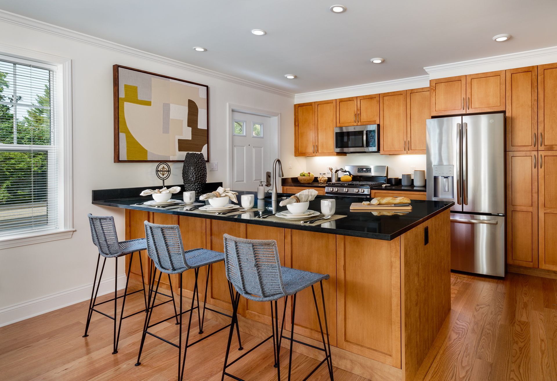 Kitchen with island, wood cabinets, stainless steel appliances, and bar stools.