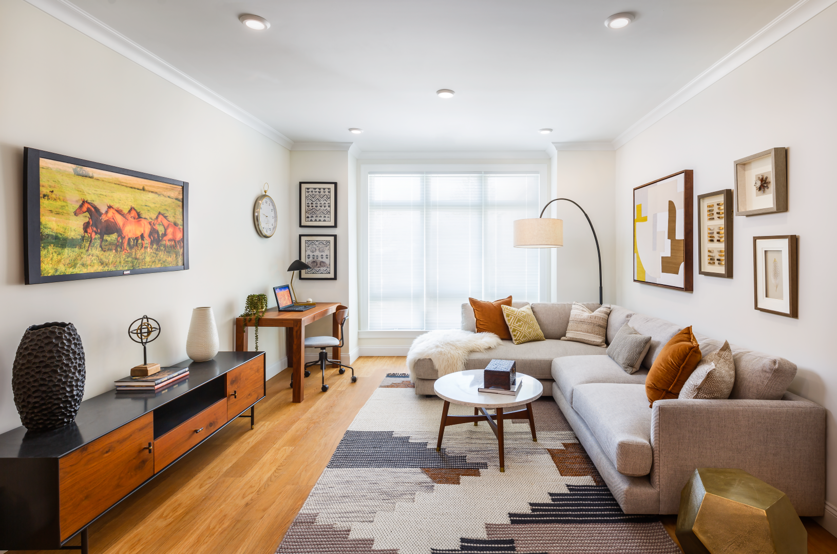 A living room with a large sectional couch and a desk