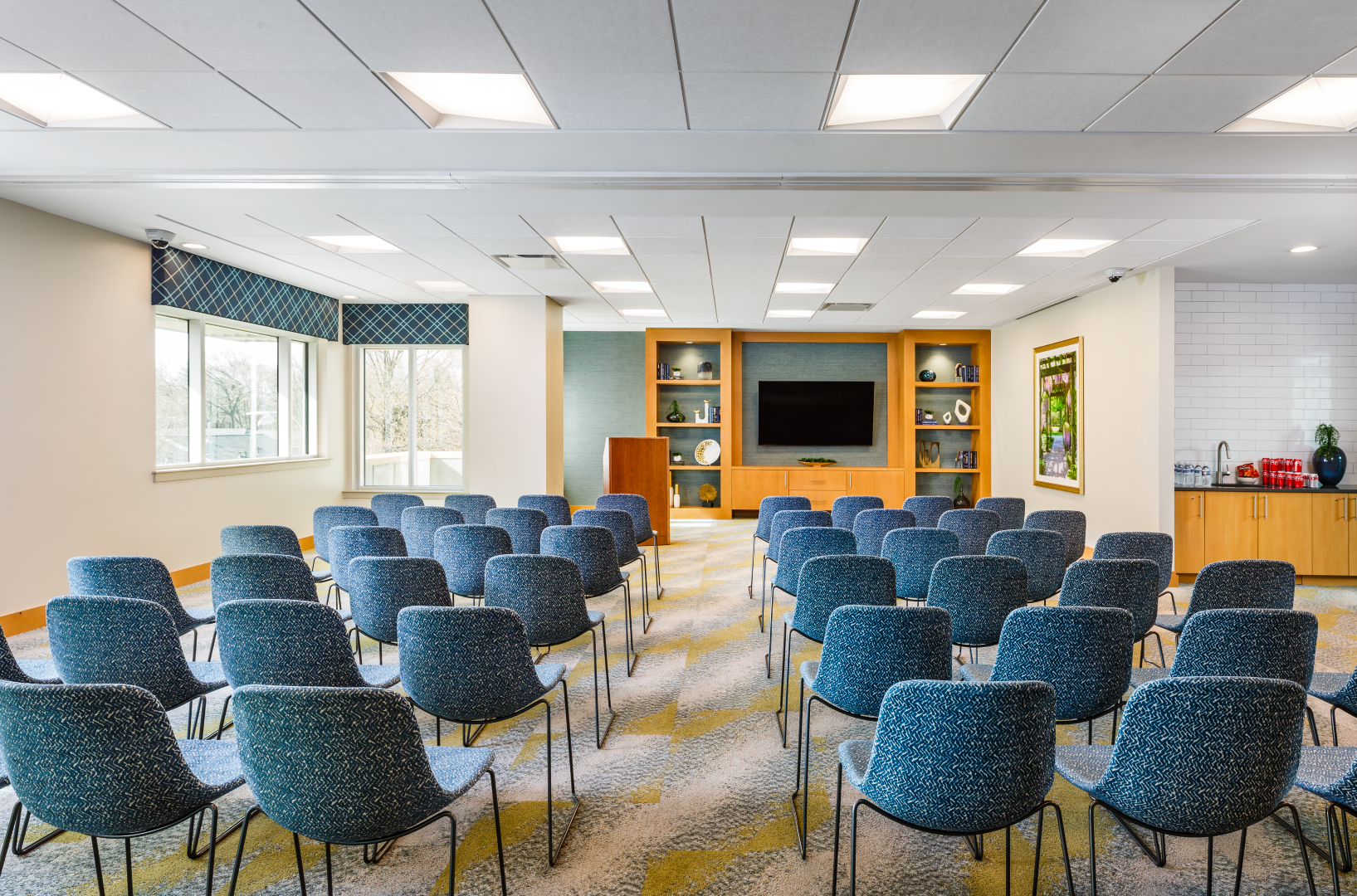 A conference room with rows of chairs and a flat screen tv.
