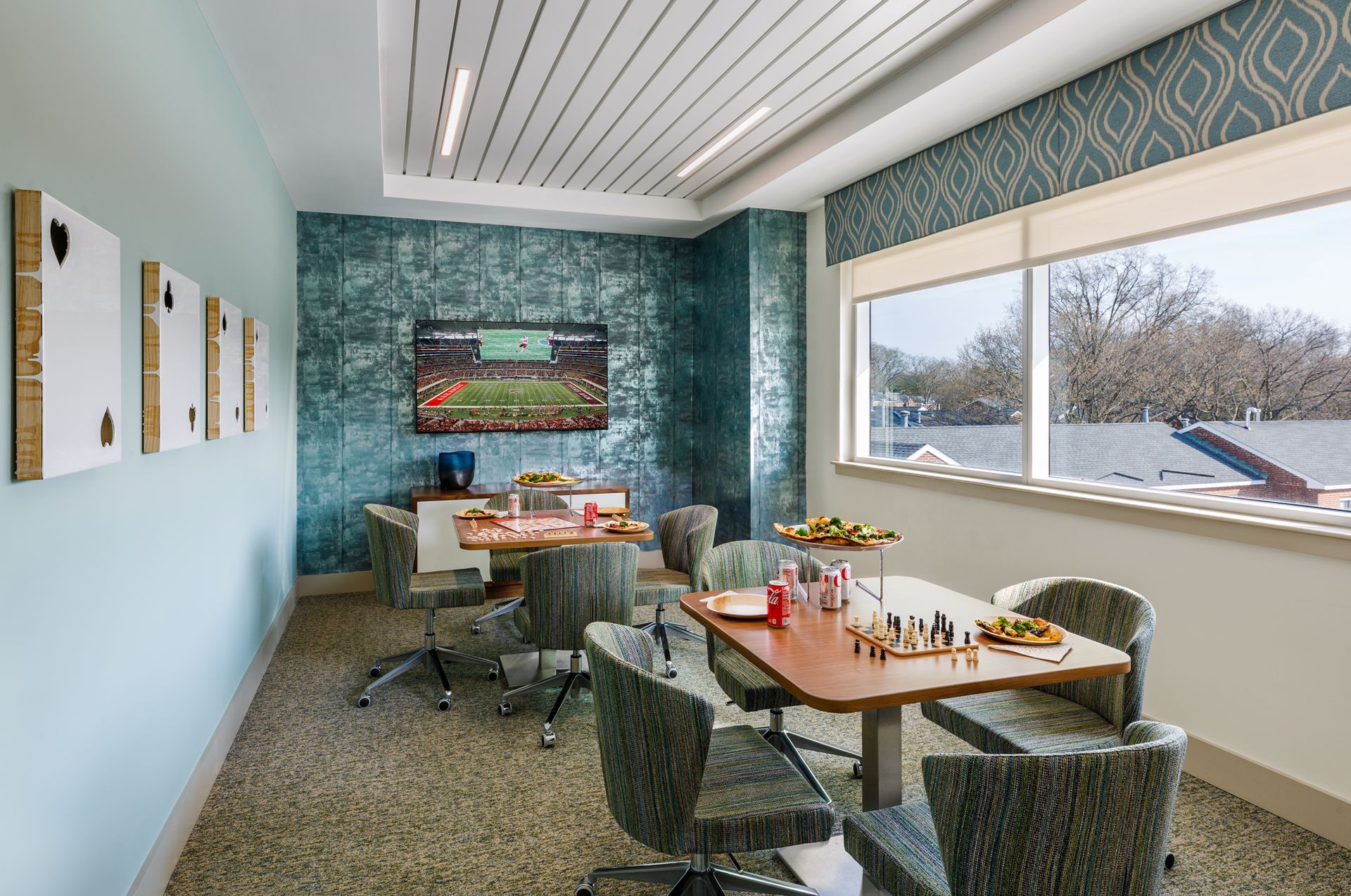 A room with a table and chairs and a television on the wall.