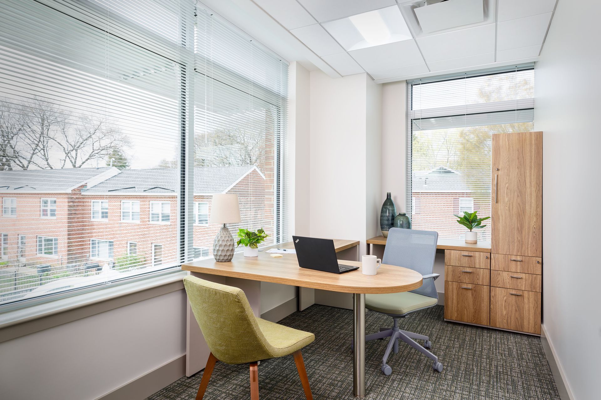 A small office with a desk and chairs and a laptop on it.