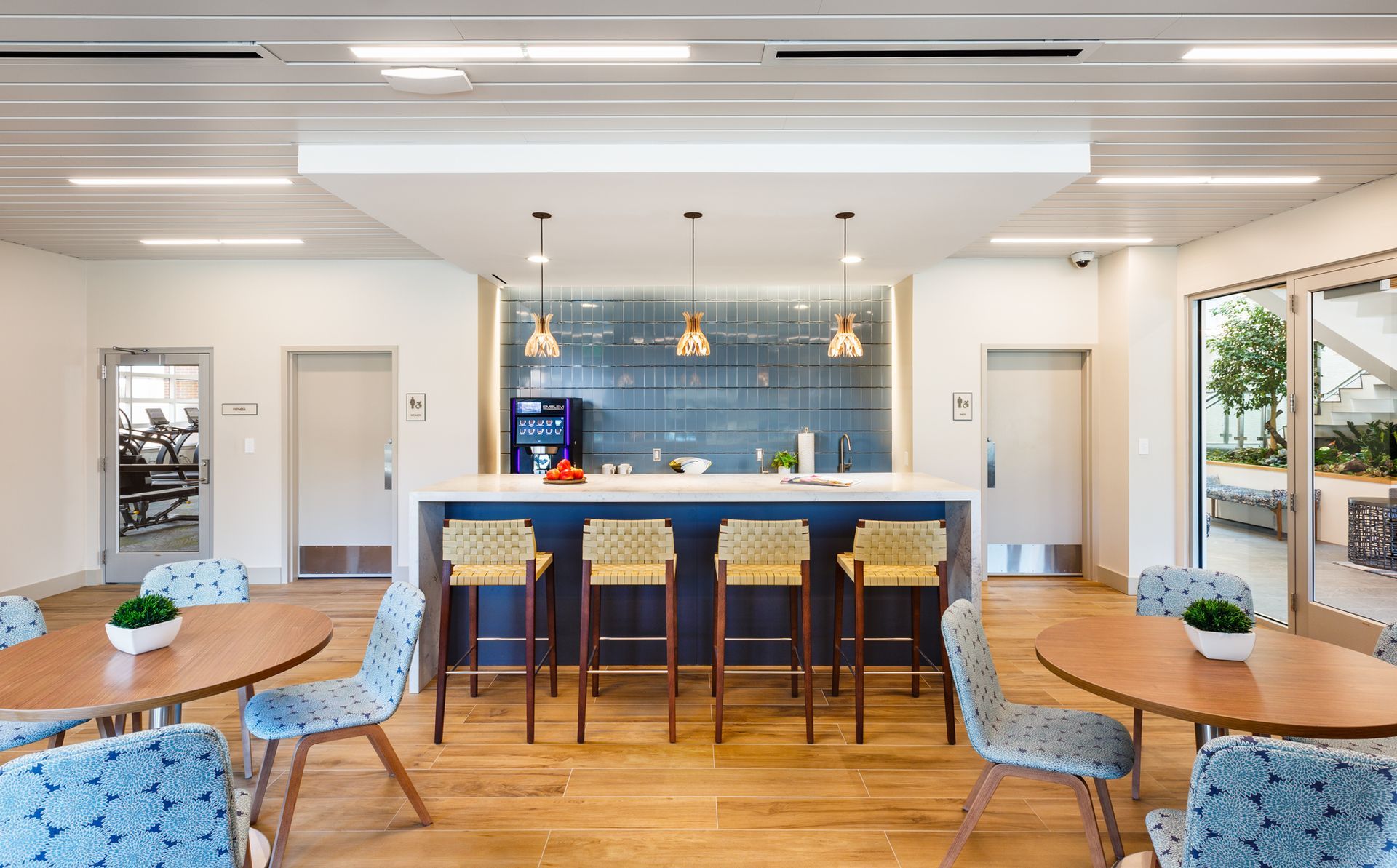 There are tables and chairs in the room with a kitchen in the background.