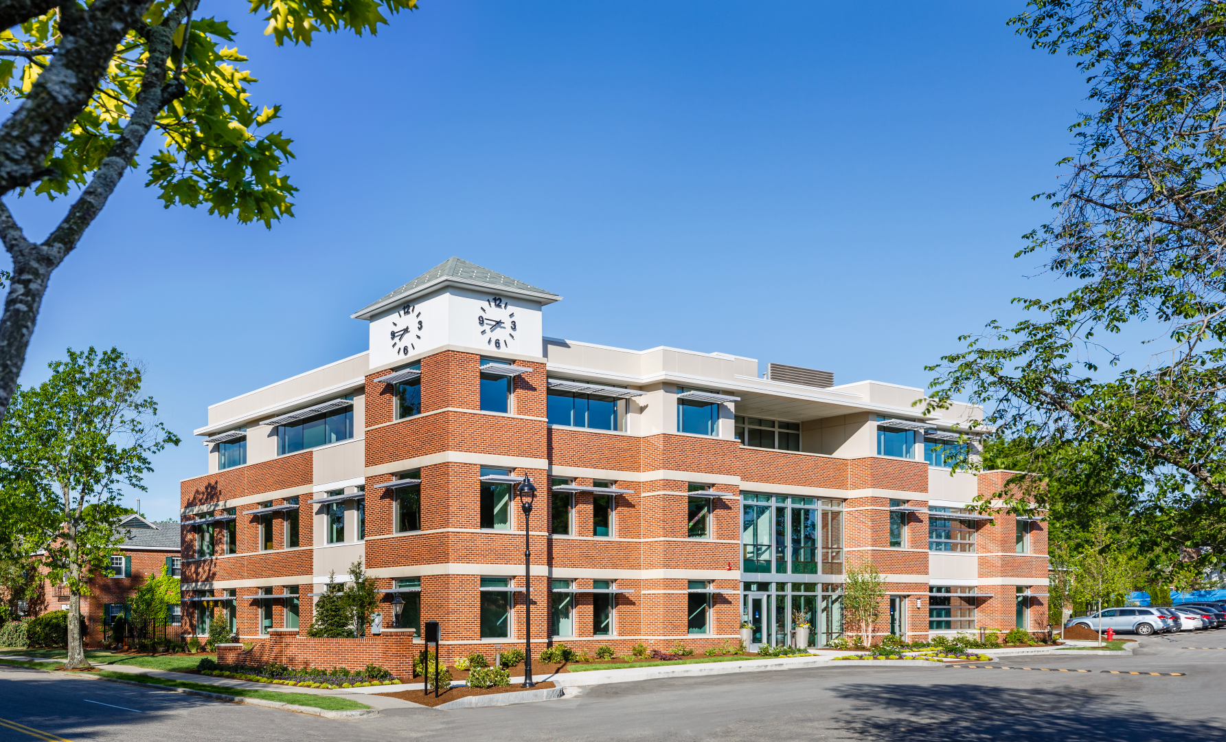 A large brick building with a lot of windows is surrounded by trees.
