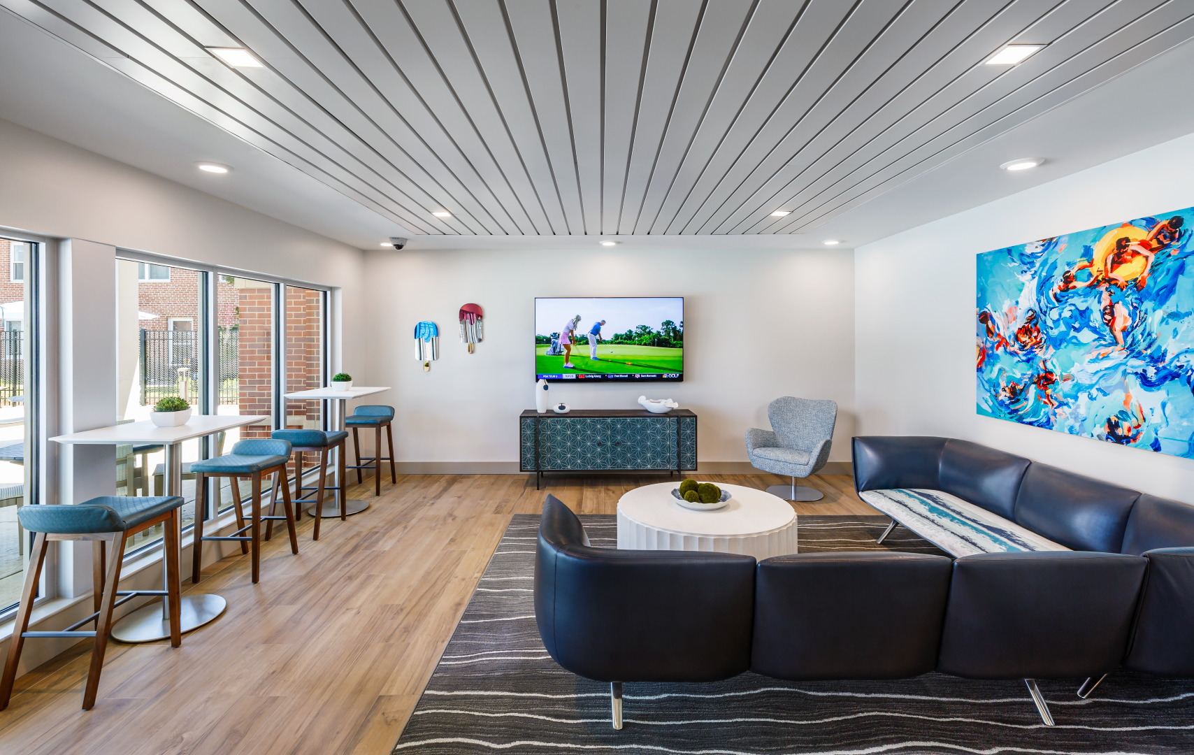 A living room with a couch , chairs , tables and a flat screen tv.