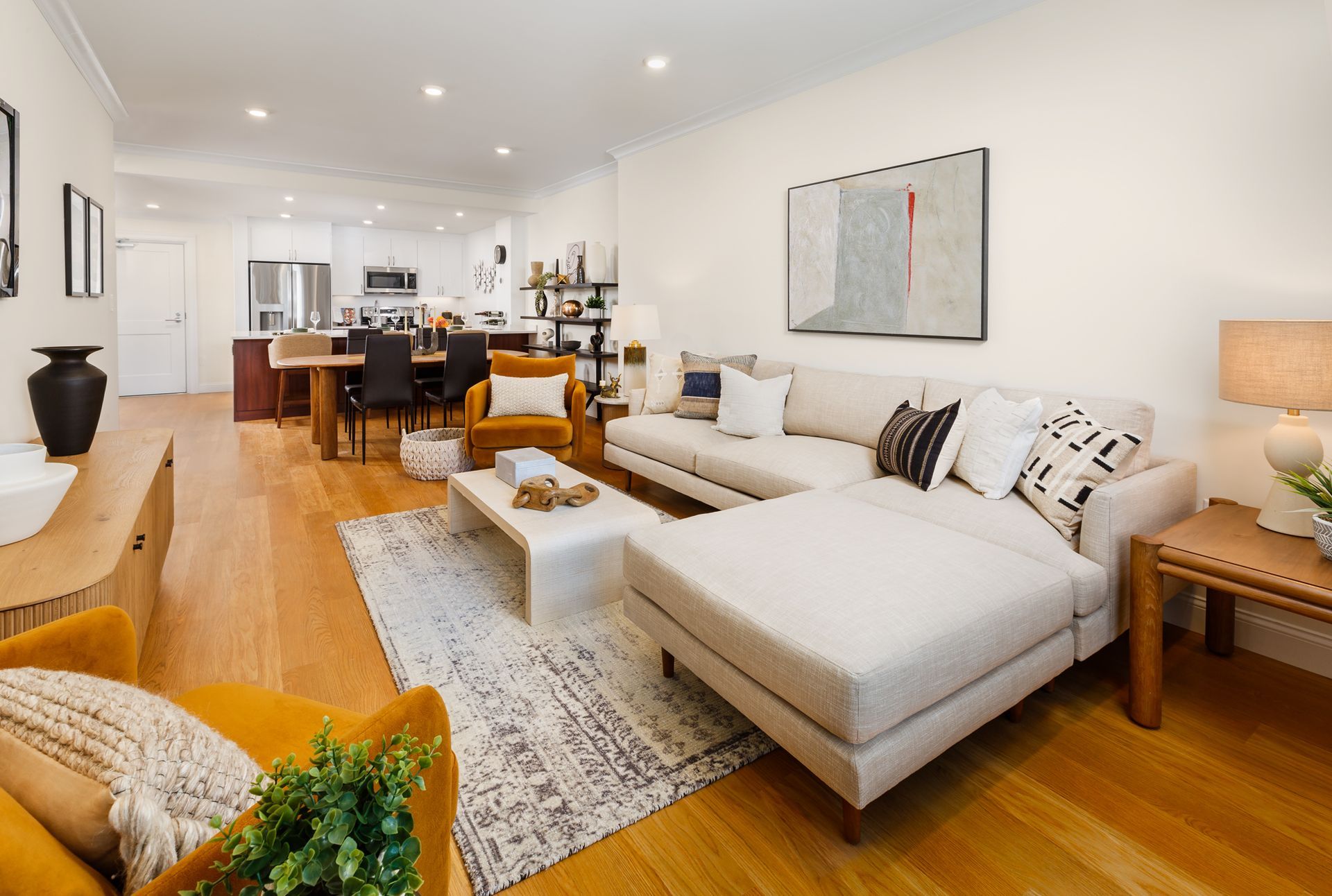 Spacious, light-filled living room with sectional sofa, coffee table, and dining area visible in the background.