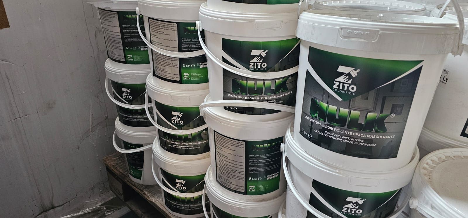 Pila di secchi bianchi con etichette verdi e nere.