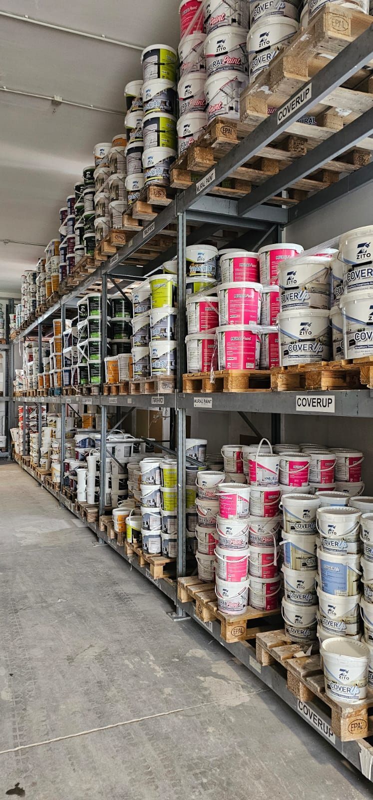 Scaffali di magazzino pieni di barattoli di vernice di vari colori.