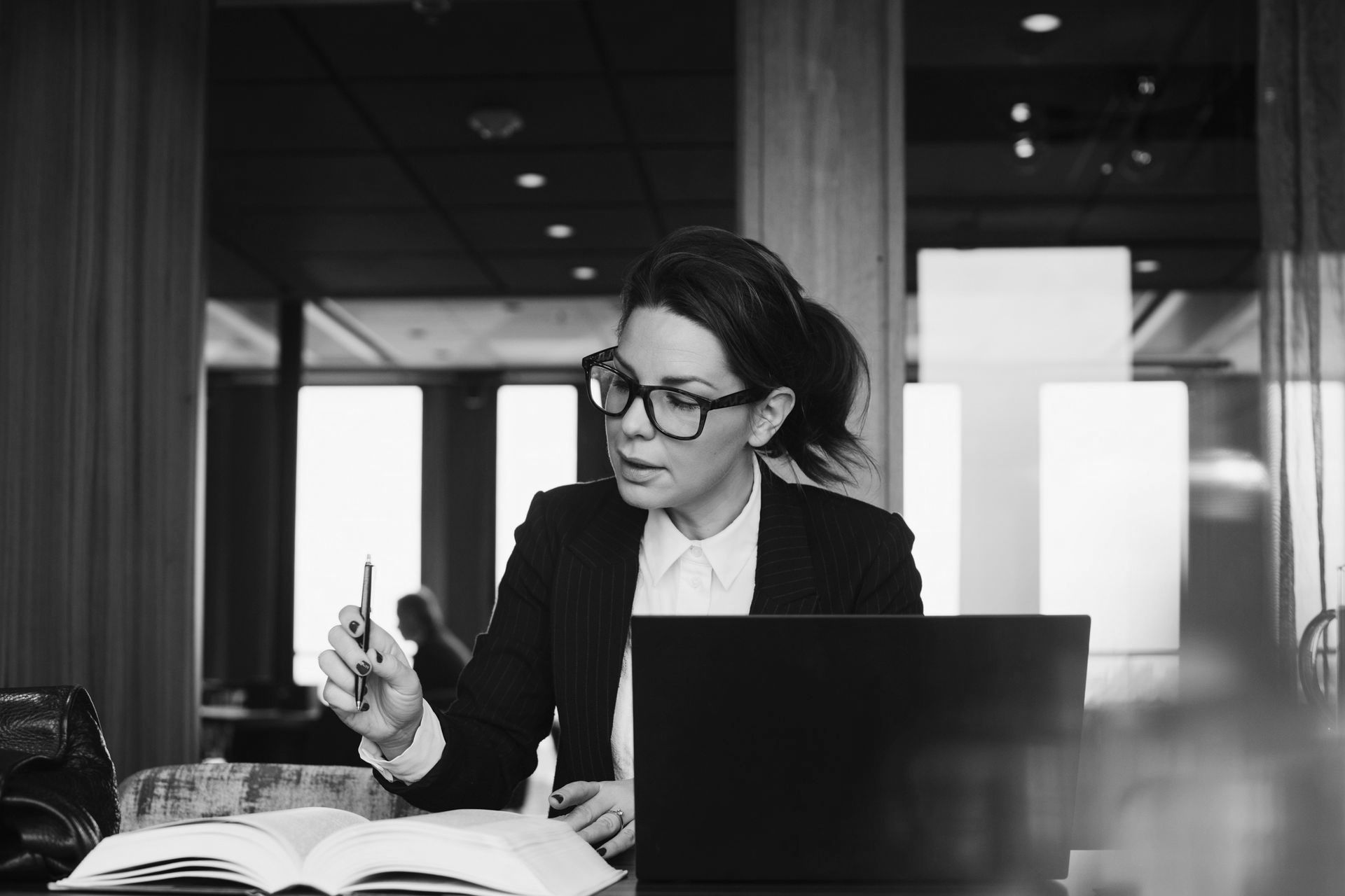 A man in a suit and tie is sitting at a desk talking on a cell phone while holding a piece of paper. A man in a suit and tie is sitting at a desk talking on a cell phone while holding a piece of paper.