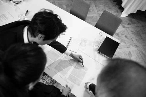 A group of people are sitting at a table writing on a piece of paper.