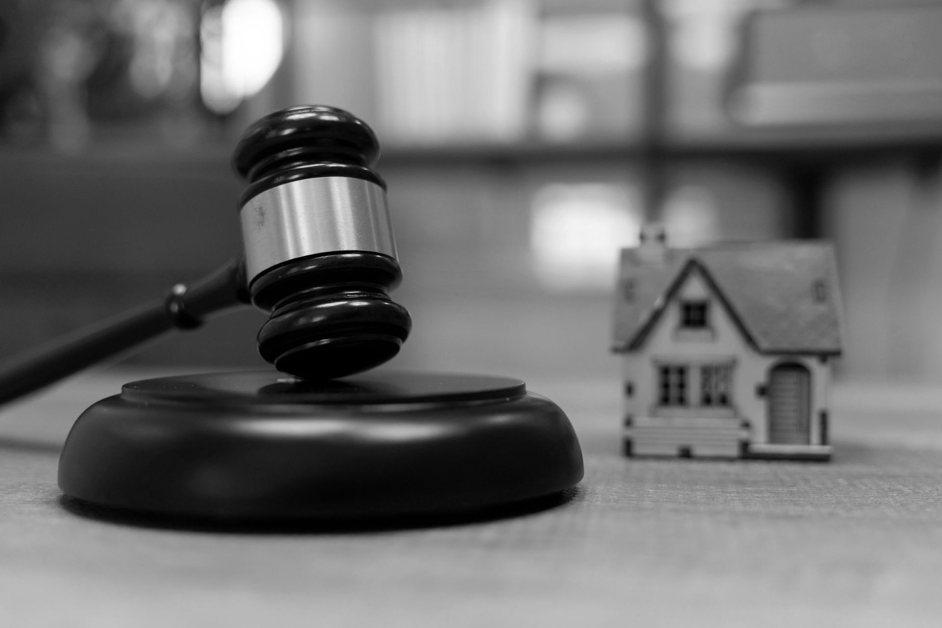 A judge's gavel is sitting on a wooden table next to a small model house. A judge's gavel is sitting on a wooden table next to a small model house.