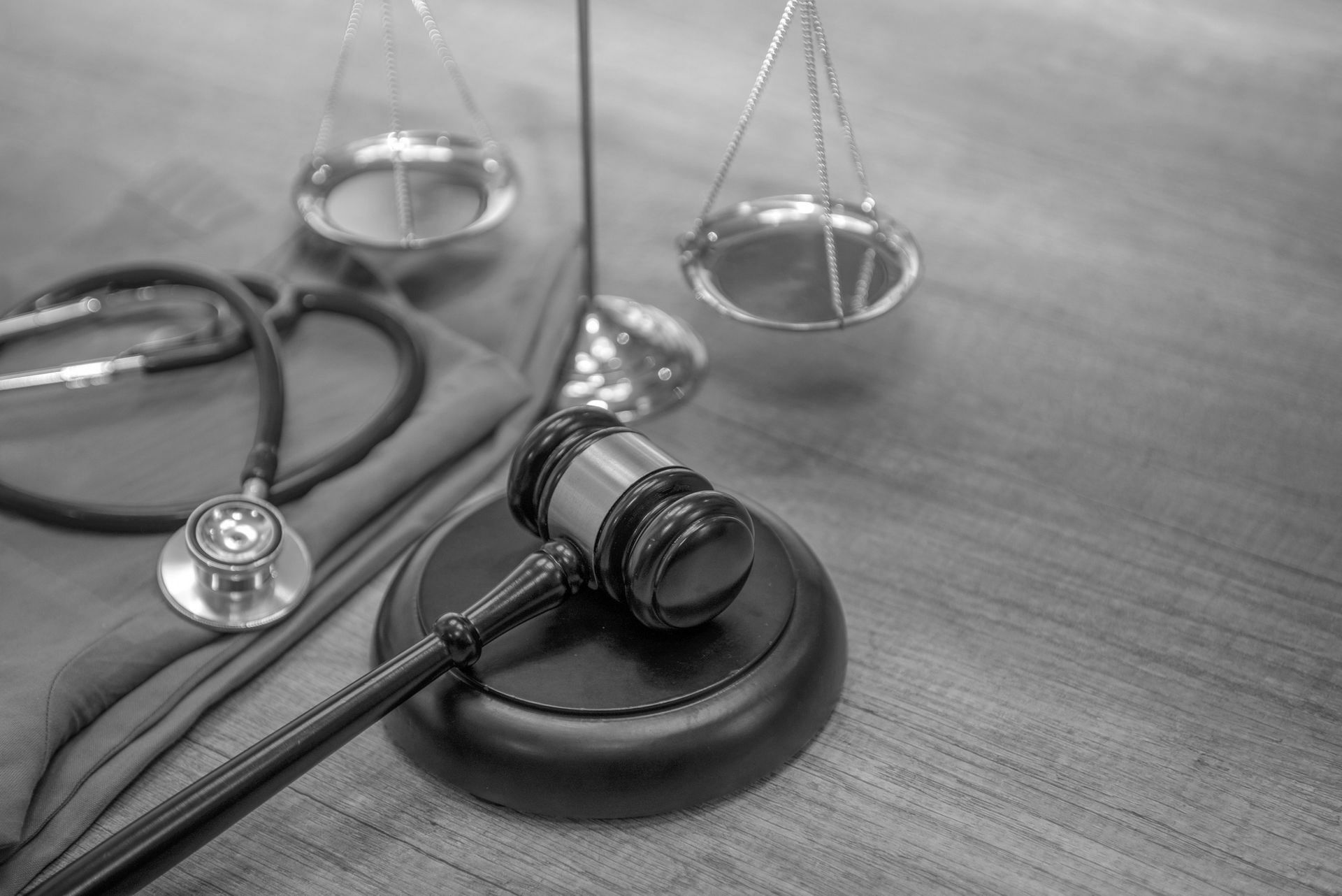 A judge's gavel is sitting on a wooden table next to a stethoscope and scales of justice.