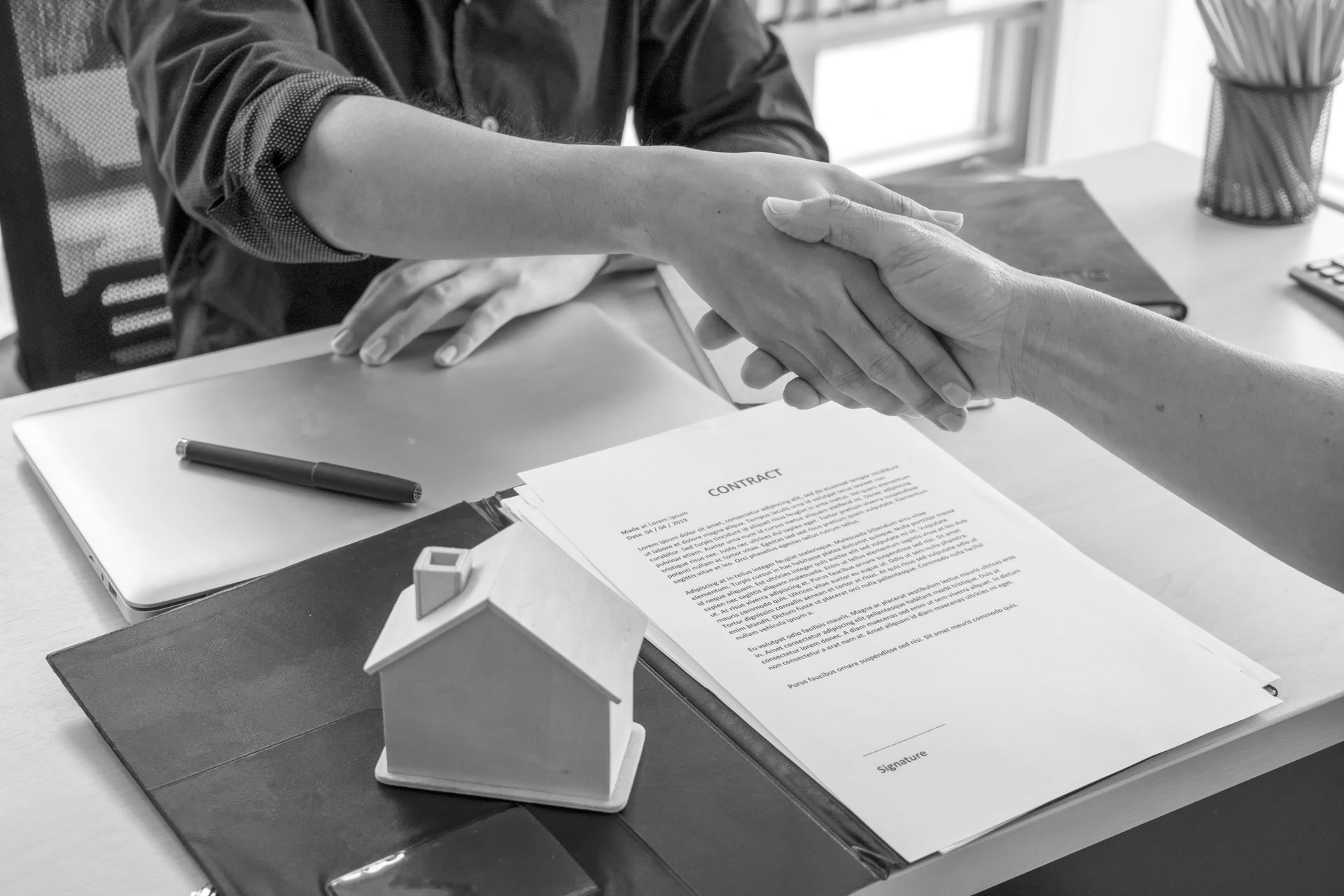 A man is shaking hands with another man while sitting at a table.