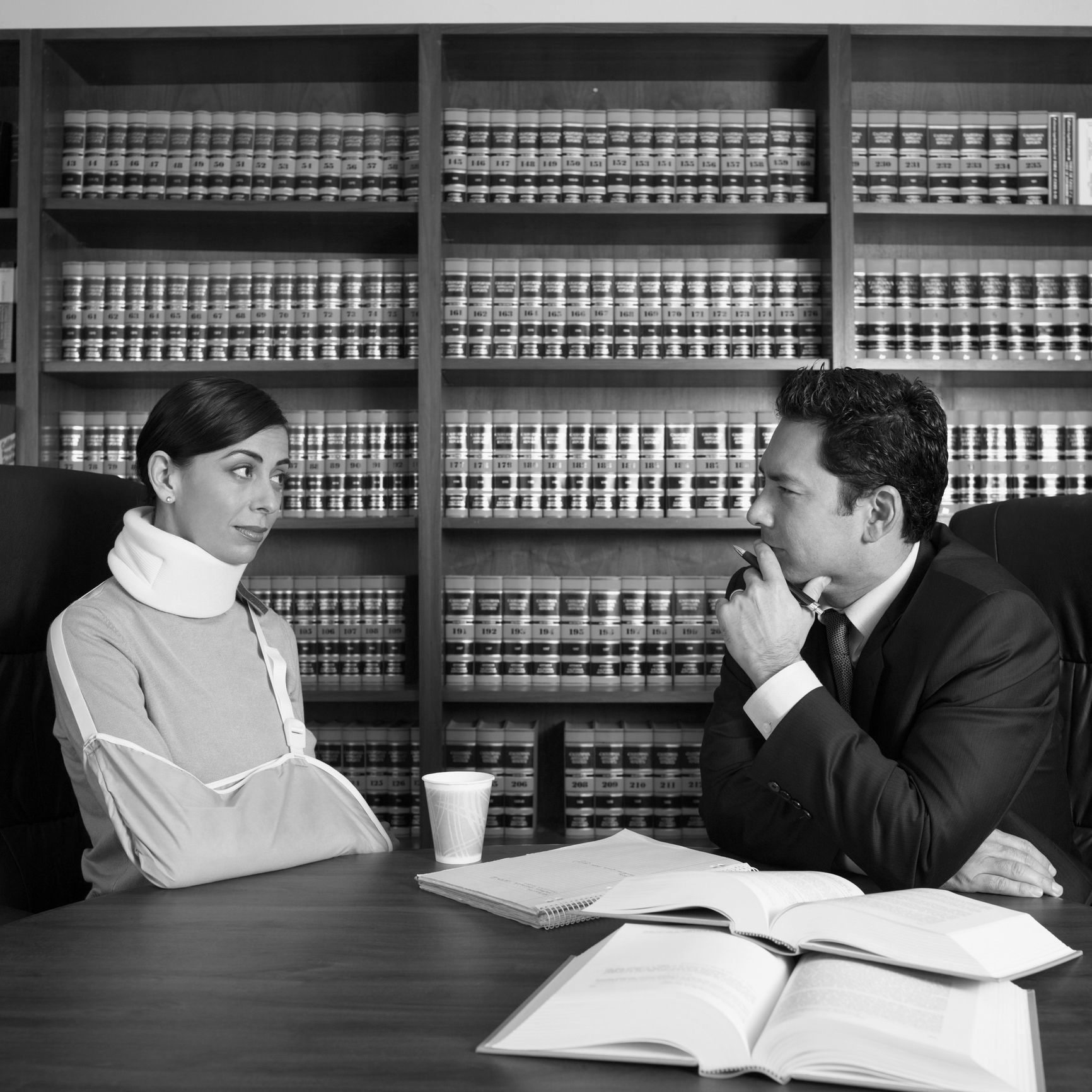 A man and a woman are sitting at a table in front of bookshelves