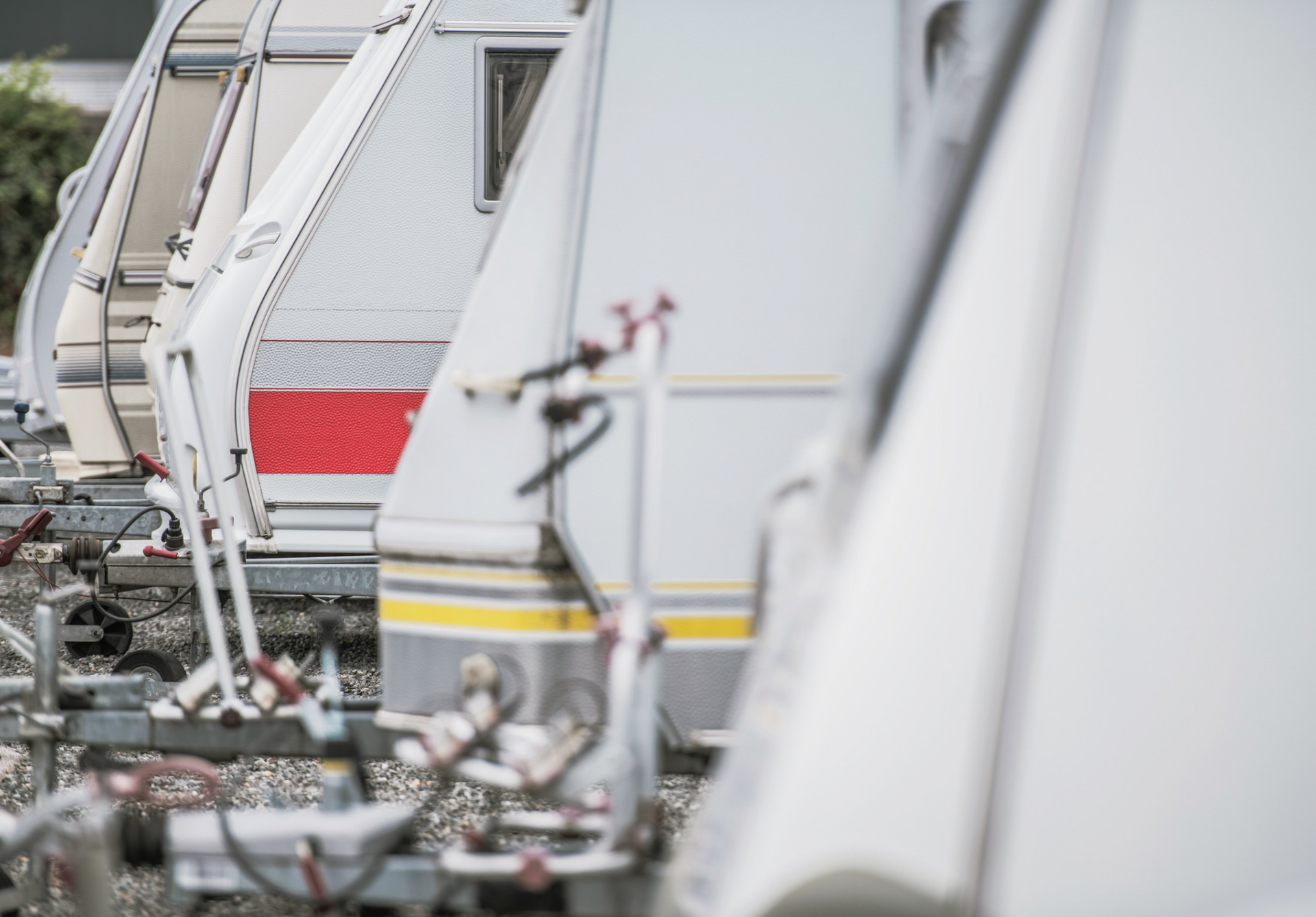 Row of white and gray campers parked outdoors, trailers in focus.