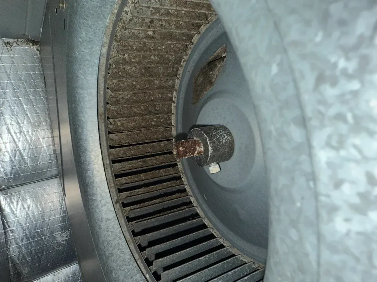 Close-up of a metal wheel hub with a rusted axle shaft and circular grooves inside a machine.