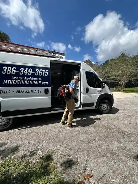 Service worker unloading equipment from a white van outside a medical office under a blue sky