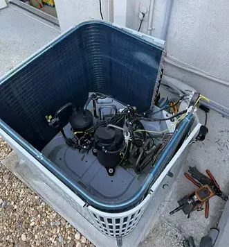 Open HVAC unit with exposed compressor and wiring beside a house exterior.