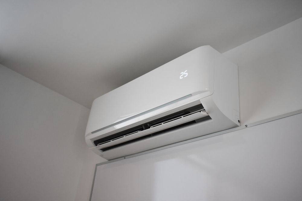 Wall-mounted white air conditioner on a light-colored interior wall